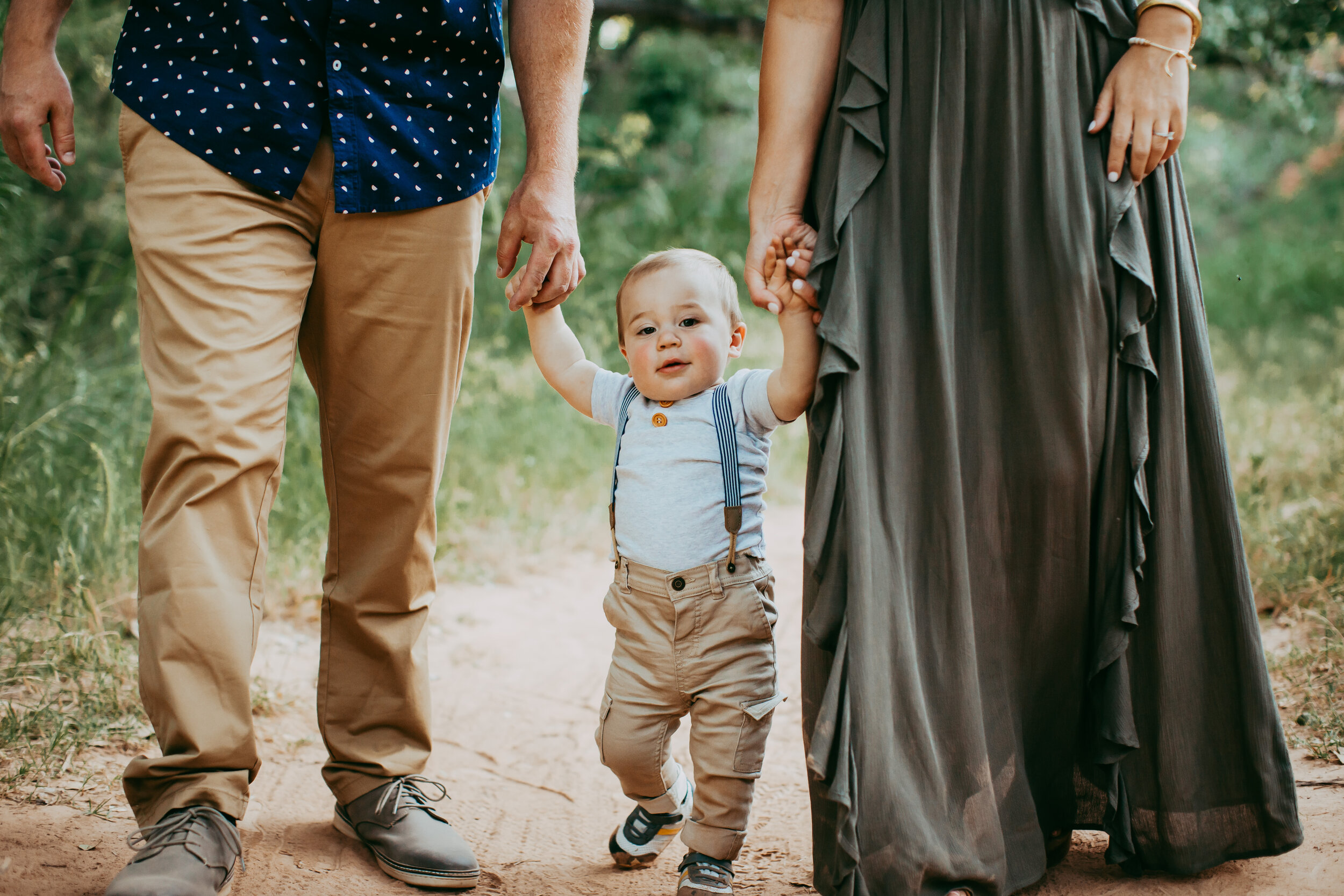  Distant shot of little one walking with mom and dad down the dirt path surrounded by green grass #tealawardphotography #texasfamilyphotographer #amarillophotographer #amarillofamilyphotographer #lifestylephotography #emotionalphotography #familyphotoshoot #family #lovingsiblings #purejoy #familyphotos #naturalfamilyinteraction 