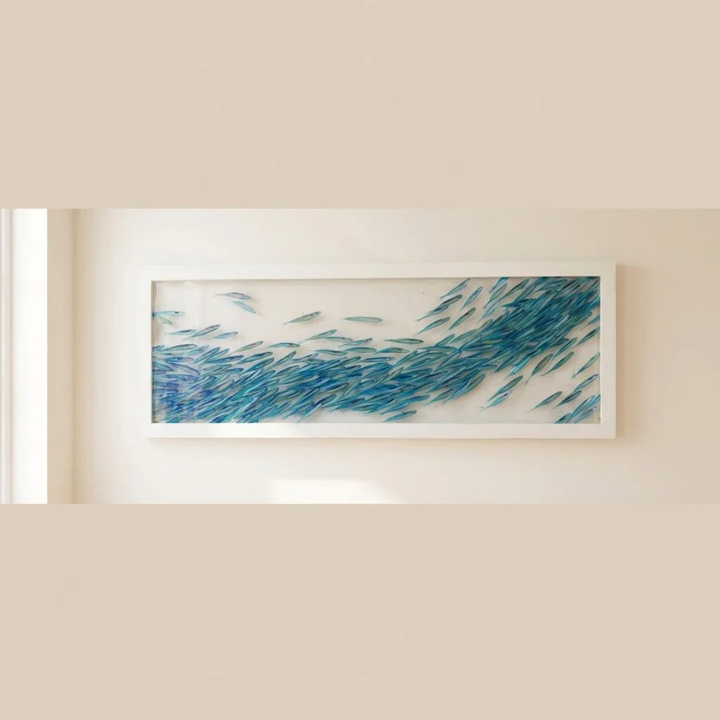 Framed artwork of a school of blue fish swimming on a white background.
