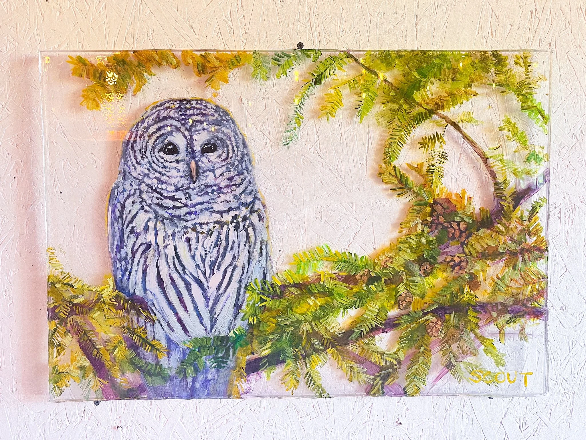 A painting of a snowy owl perched among green pine branches, signed by an artist named Scout.