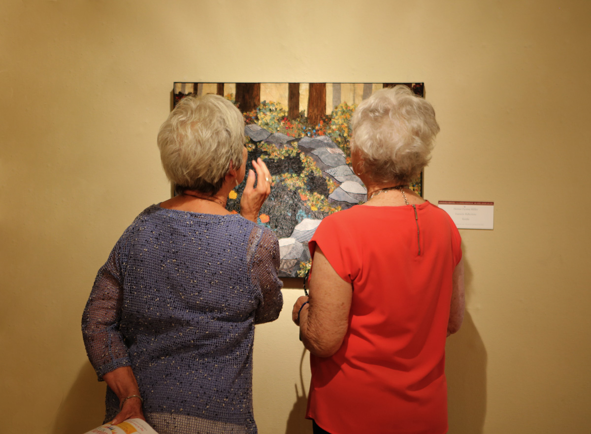 Visitors admire the textile art by Denise Oyama Miller, "Yosemite Reflections”