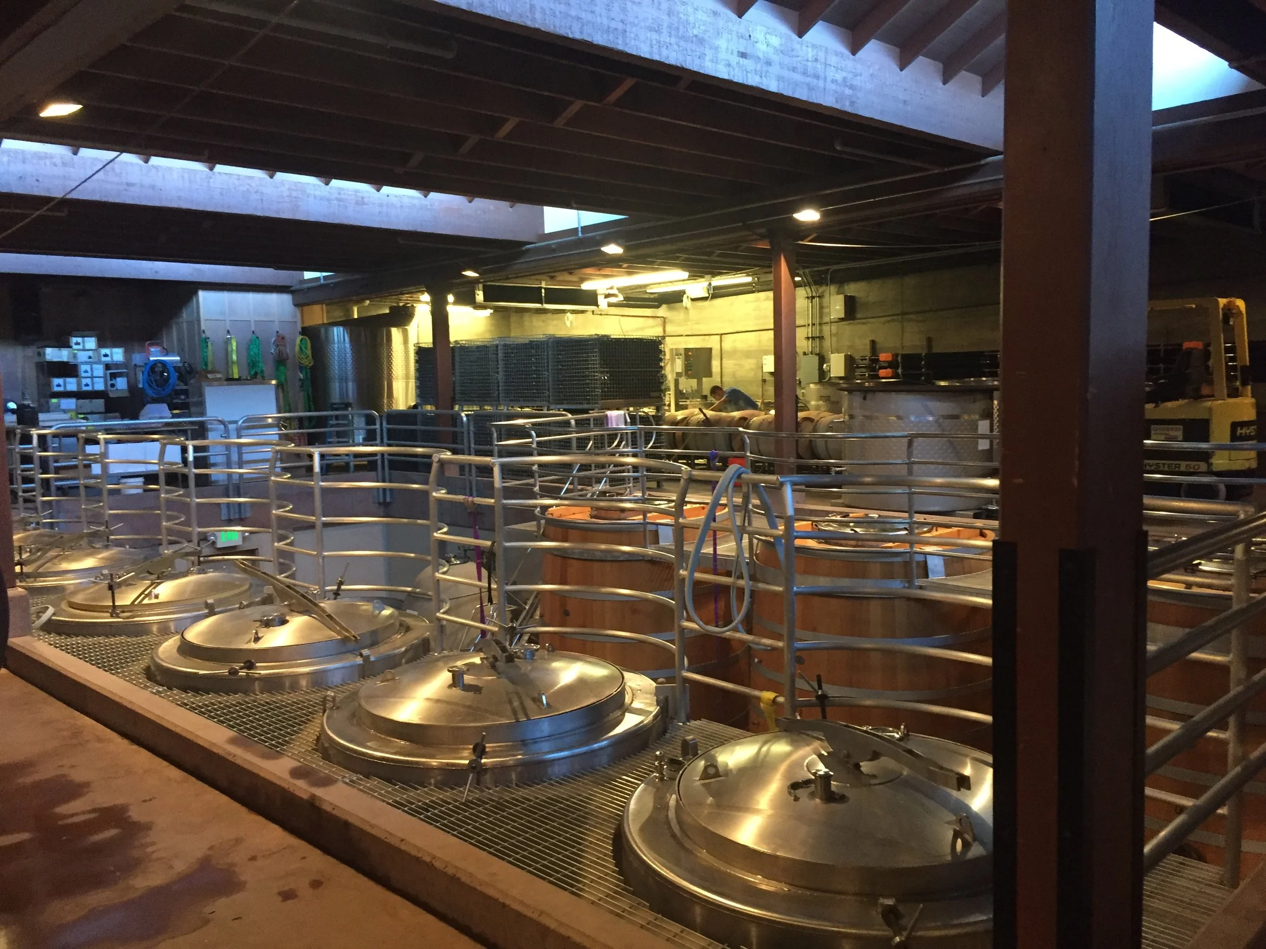 Large stainless steel fermentation tanks in action during crush and production.