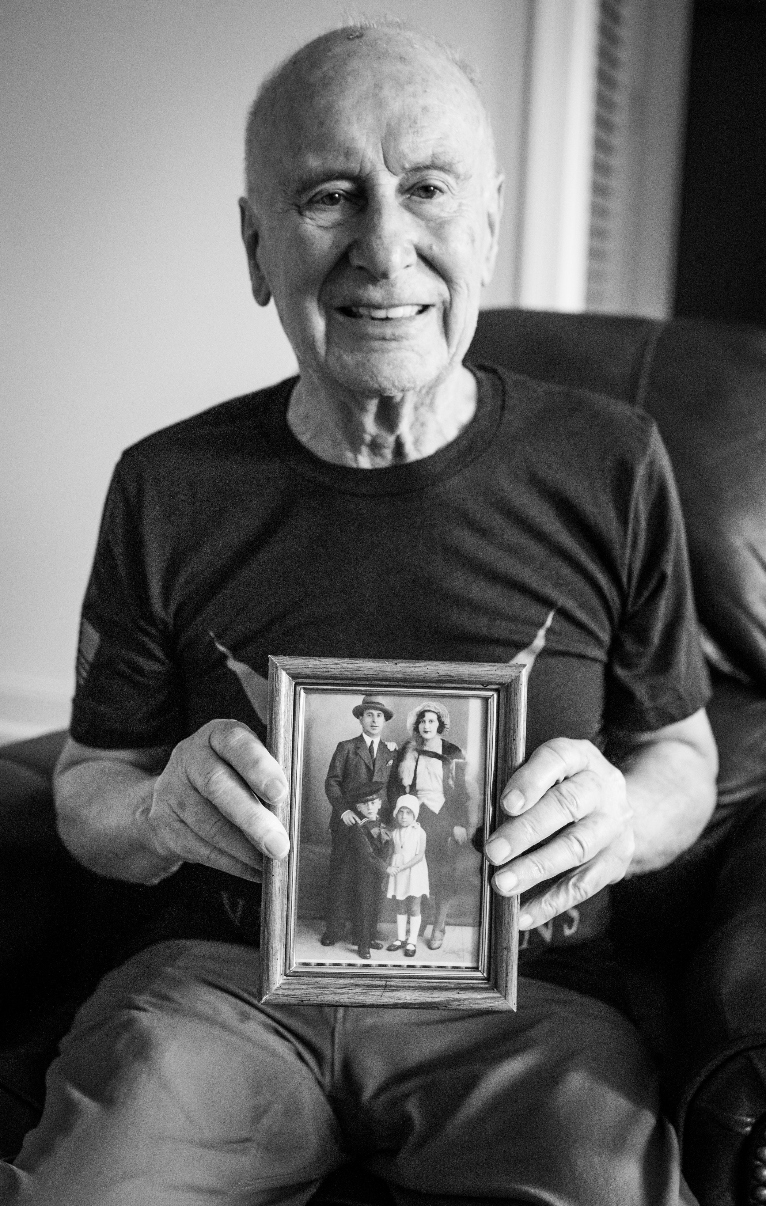 John holds a photograph of his family. This was shortly before his mother passed away.