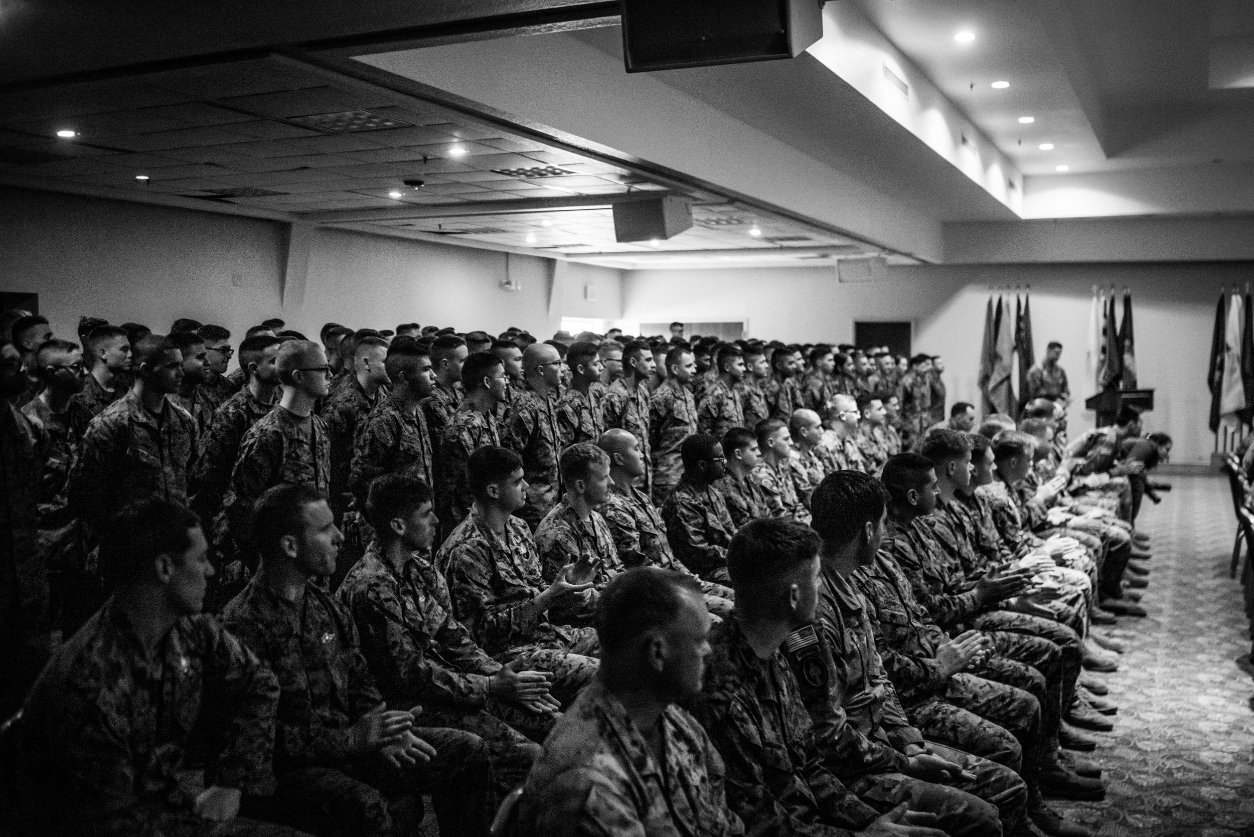 Marines, Navy Corpsmen, and Soldiers listen in as Woody speaks about his life.
