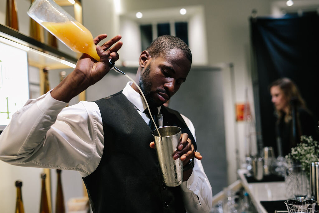 barman pouring a drink from orange bottle