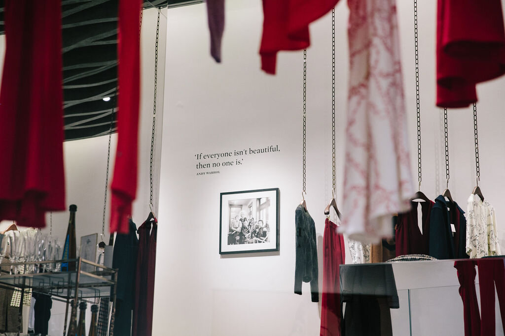 clothes hanging from the ceiling in a shop with piece of art in the middle