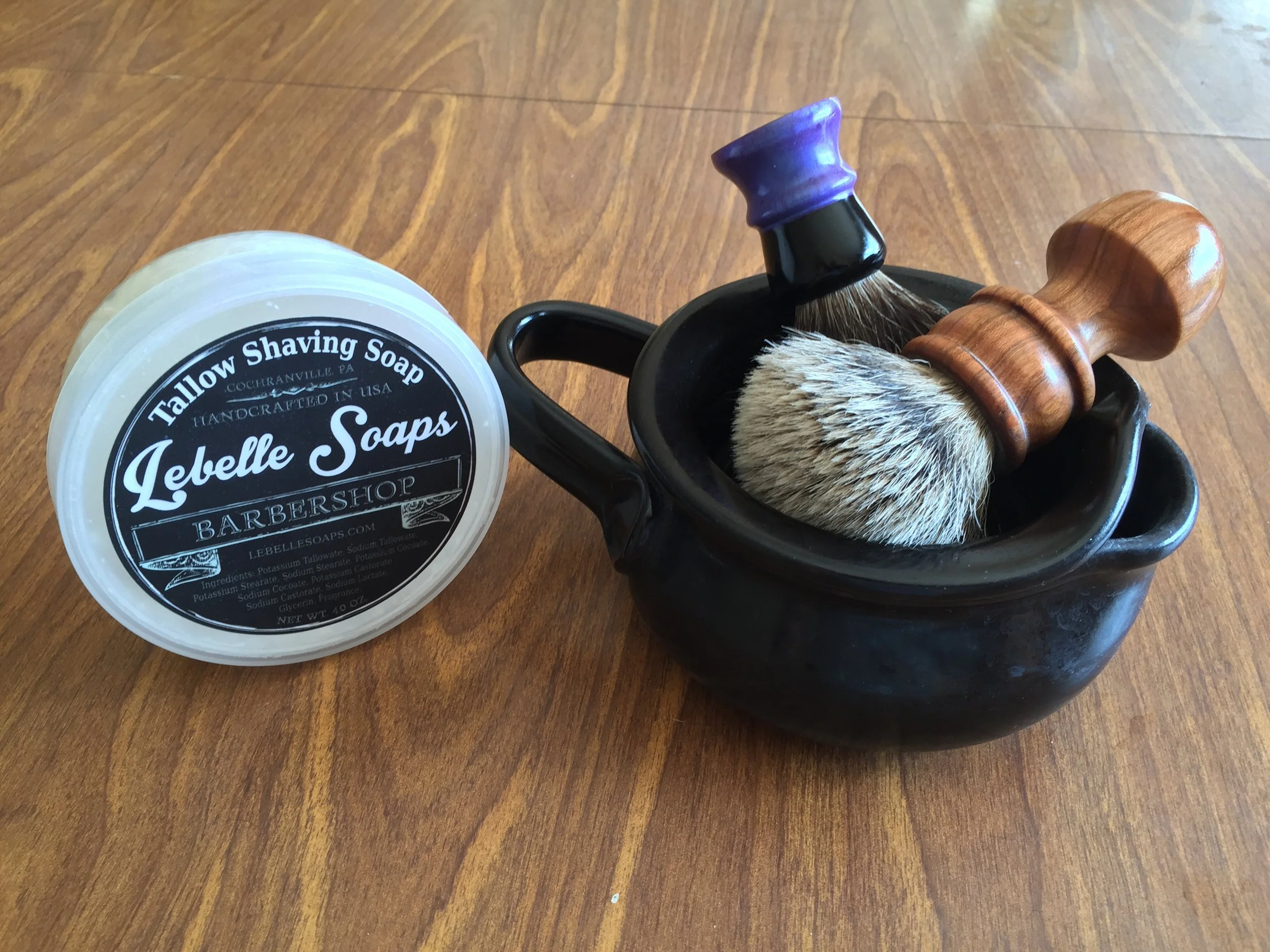 An example of a Pottersong shave scuttle with two types of brushes: the long handled Fretzwerks turned silvertip badger brush, and a facial lathering short handle brush in the back. Featured in the photo is a good starter pack for wet shaving.