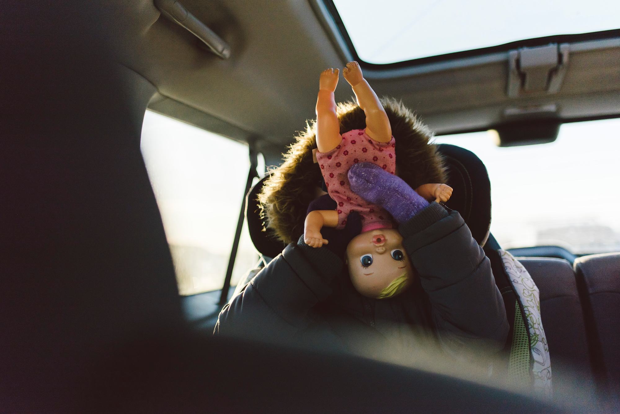 Girl holding baby doll in car