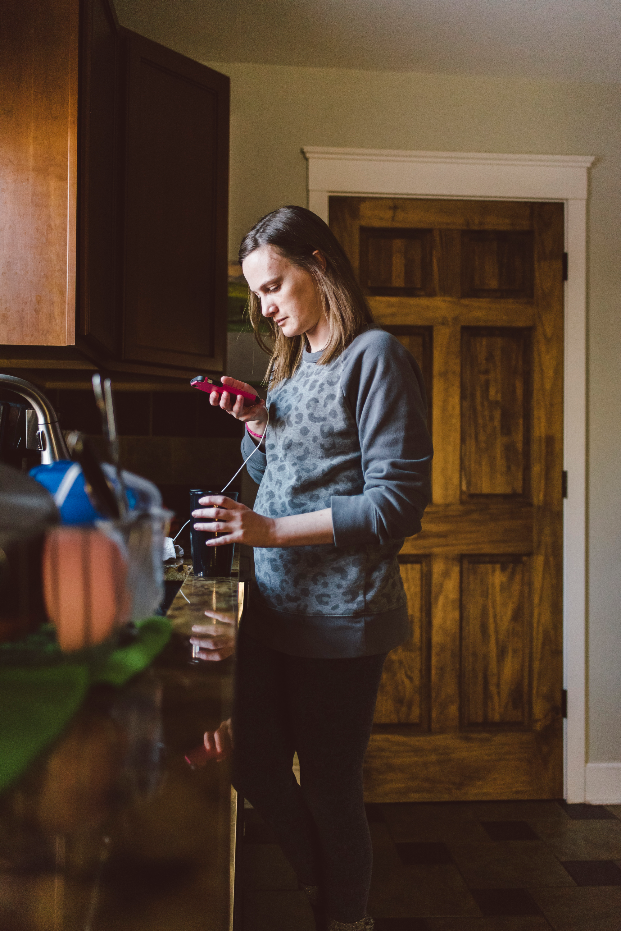 Woman looking at phone by kitchen sink