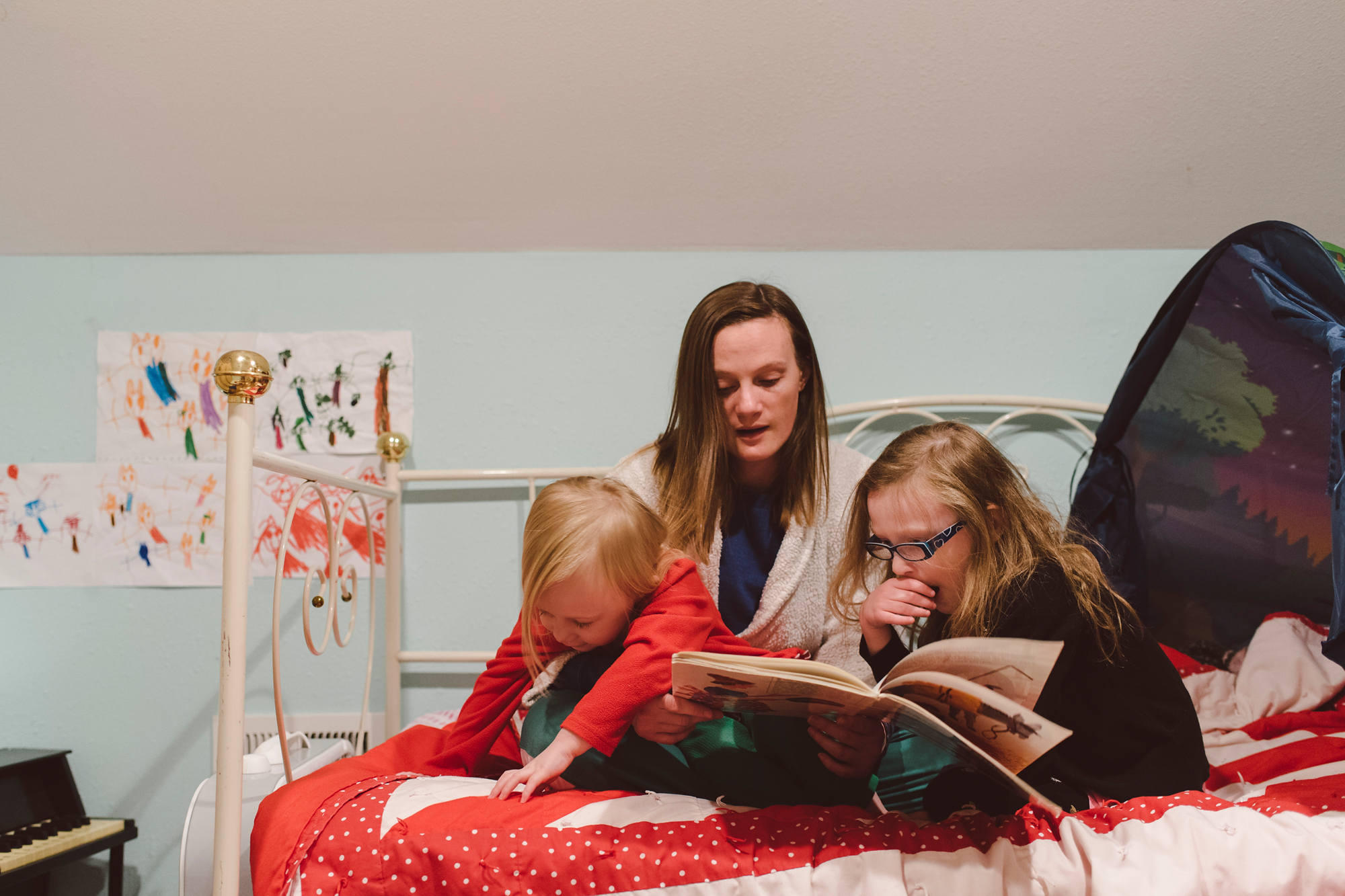 Mother reading book to two daughters
