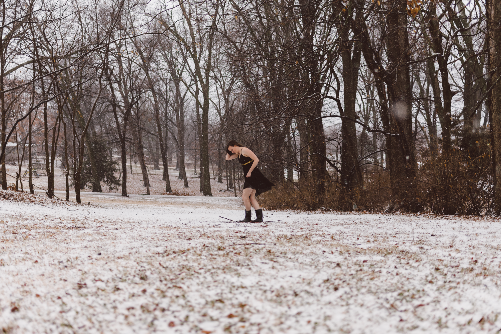 Girl with black dress standing in snow