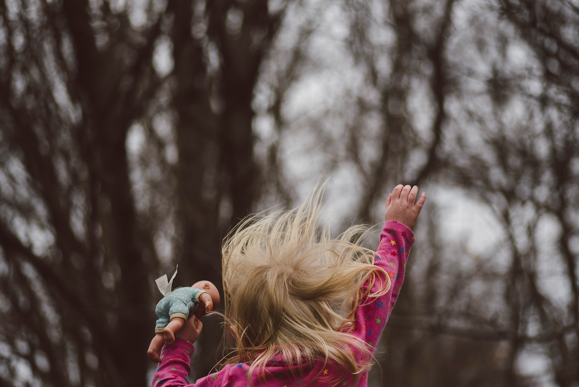 Toddler jumping with hair flying holding doll