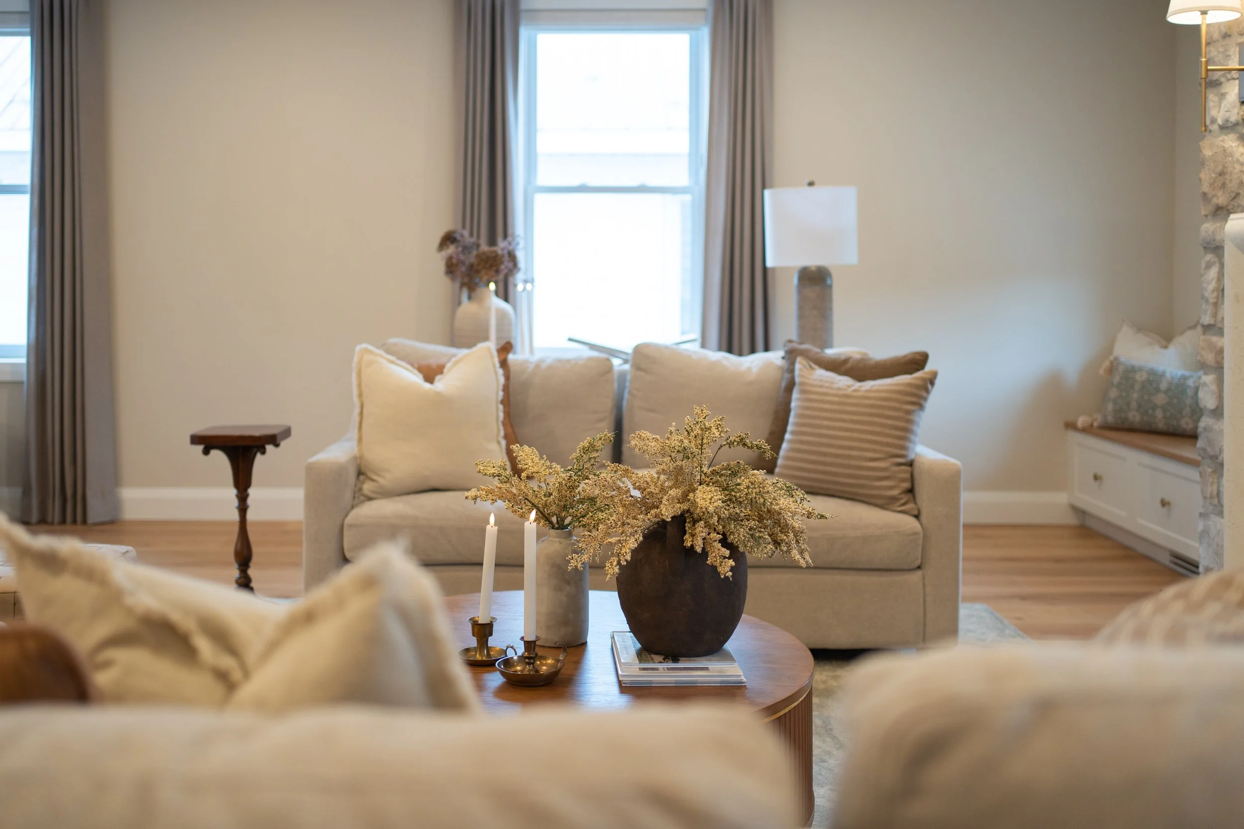 Open living space centered around a stone fireplace with a custom mantle and symmetrical seating arrangement