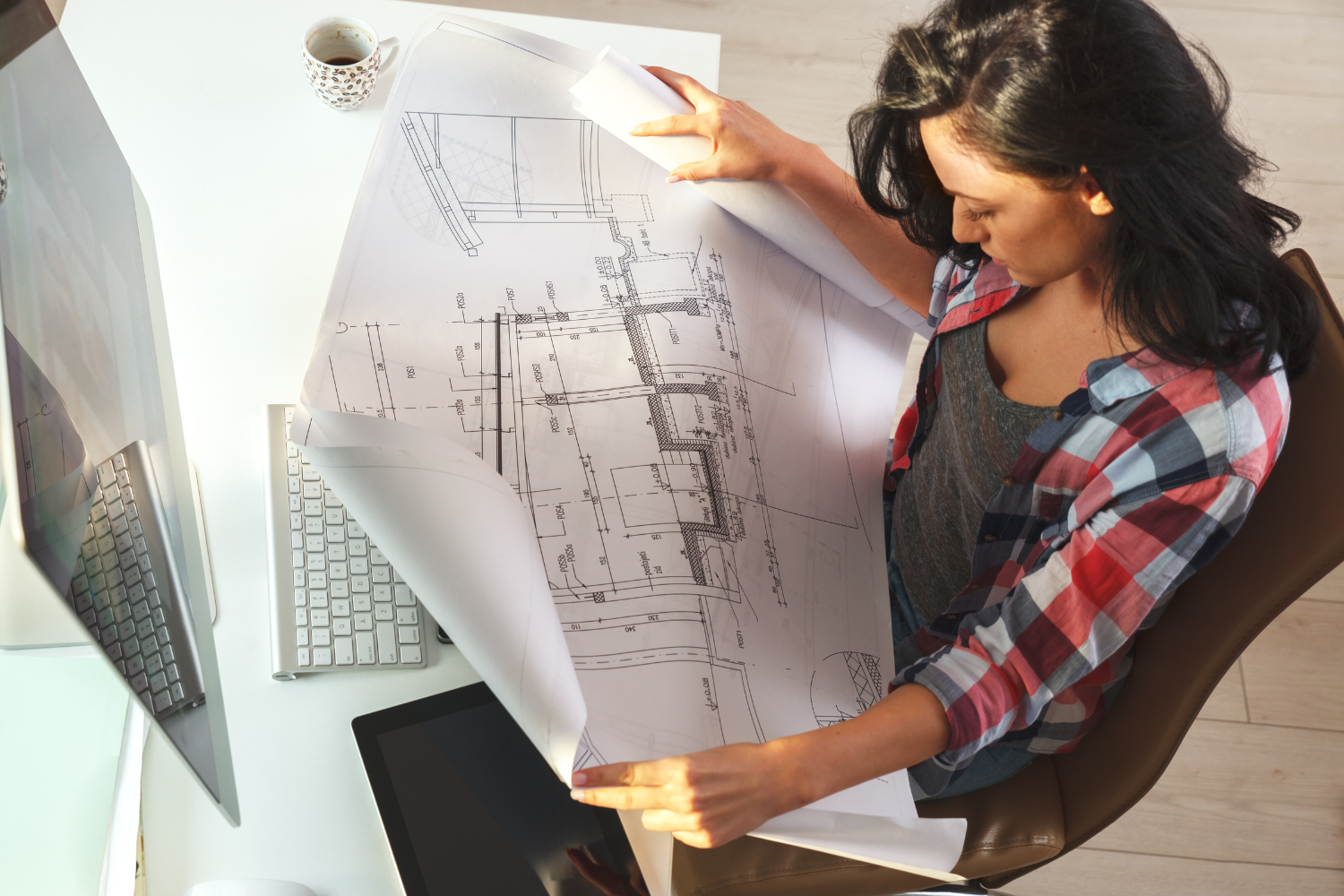 woman holding house blueprints in office want to build a custom home these are the roles you'll need.png