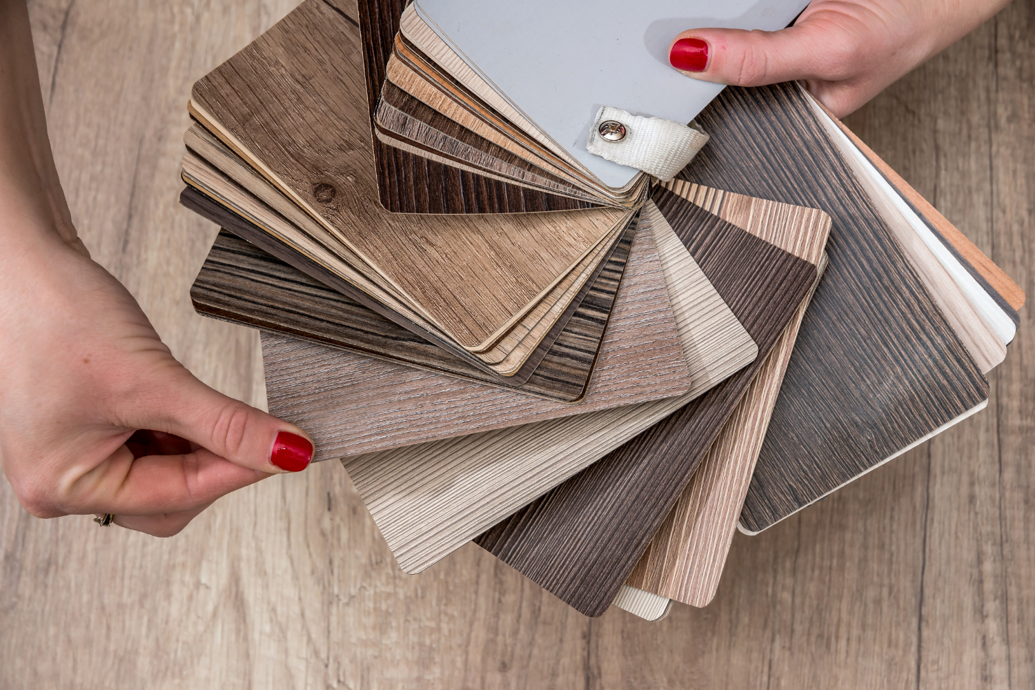 samples of luxury vinyl plank flooring fanned out in womans hands pros and cons lvt vs. lvp flooring in home.png