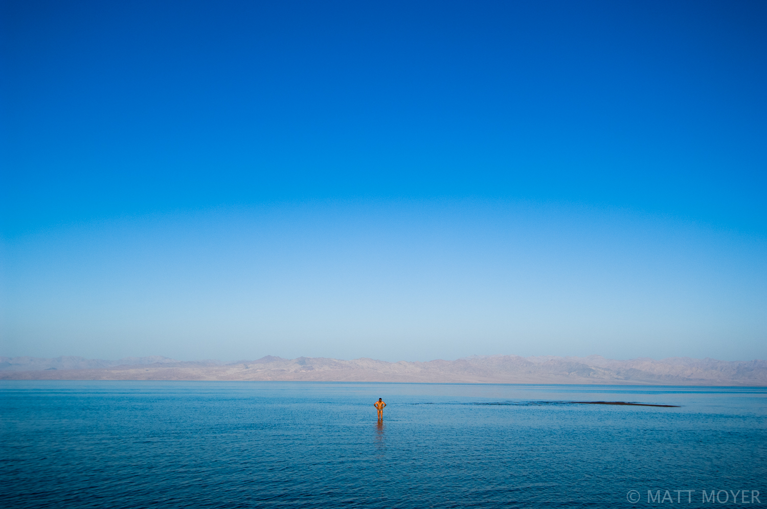  A tourist wades in the tranquil waters of the Gulf of Aqaba along the Sinai coast as Saudi Arabia rises in the distance. 