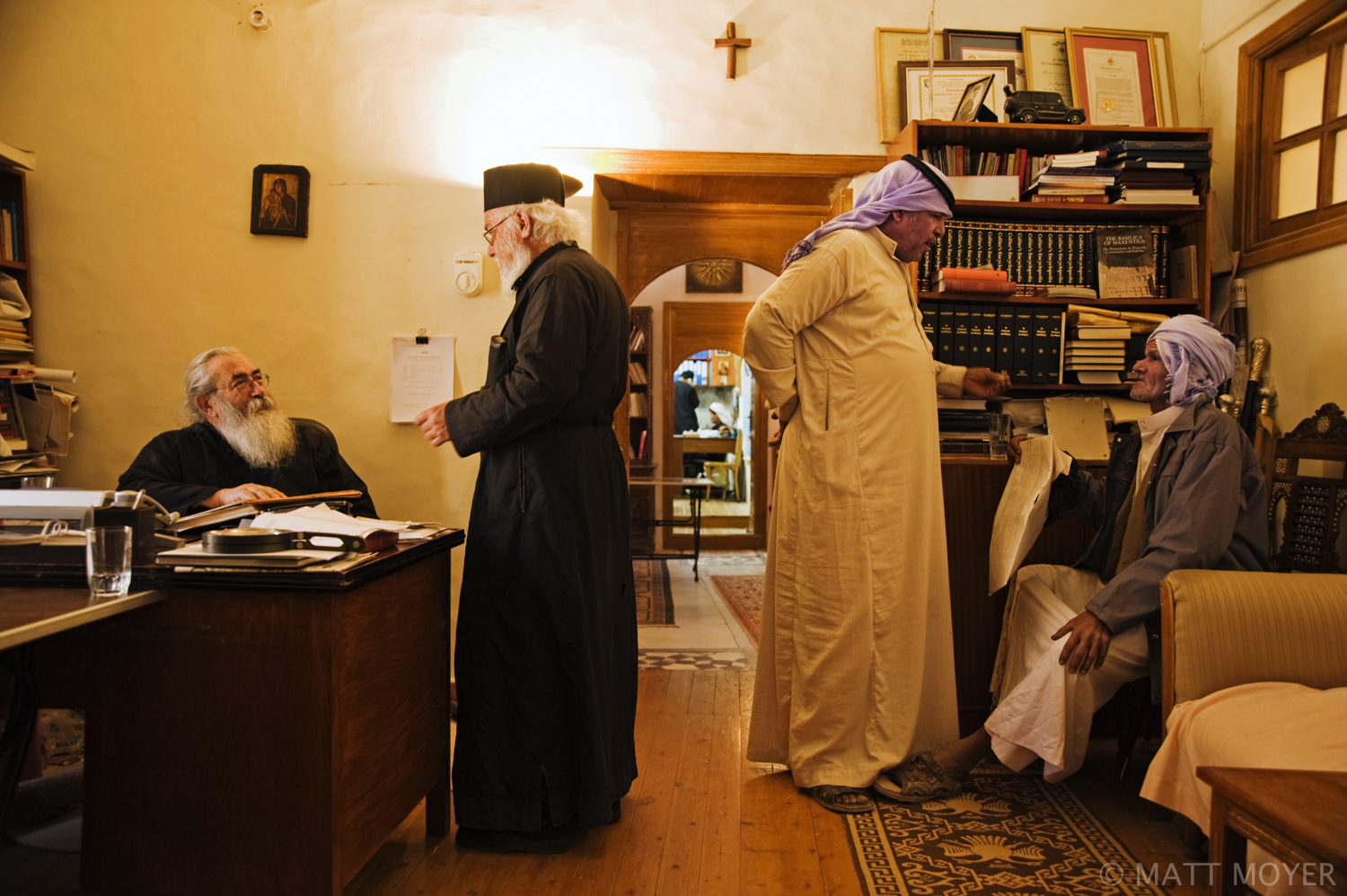  Archbishop Damianos, far left, speaks with another monk as bedouin tribal chief, Mohammed Oude, second from right, speaks with Salam Hussein. Hussein brought X-rays of his injured leg for the archbishop to look at. The bedouin work closely with the 