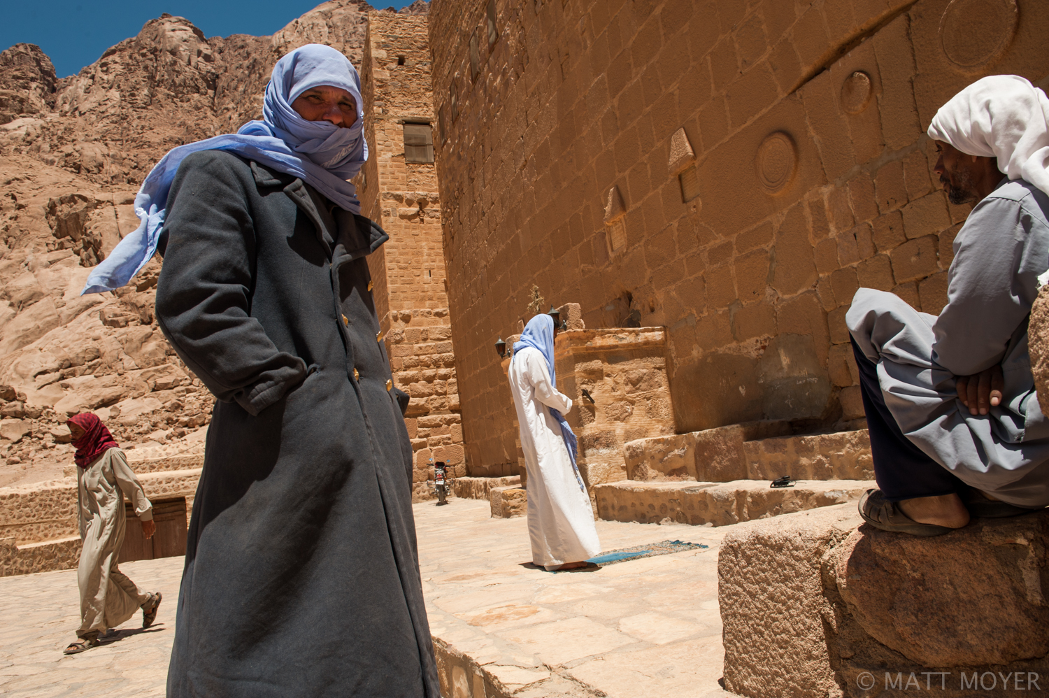  A bedouin man prays outside the entrance of the Monastery of St. Catherine as other bedouins look on in Saint Catherine Egypt. 