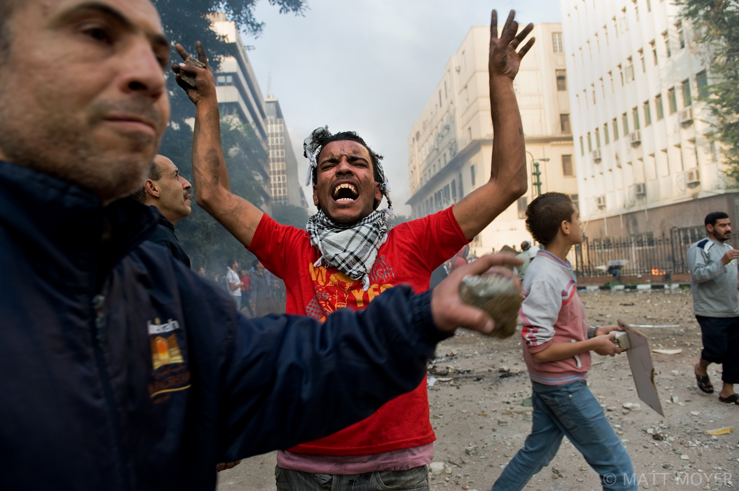  An Egyptian protester reacts as others prepare to throw stones at government forces during clashes that erupted after a pro-democracy sit-in was forcefully broken up by government troops in Cairo, Egypt. 