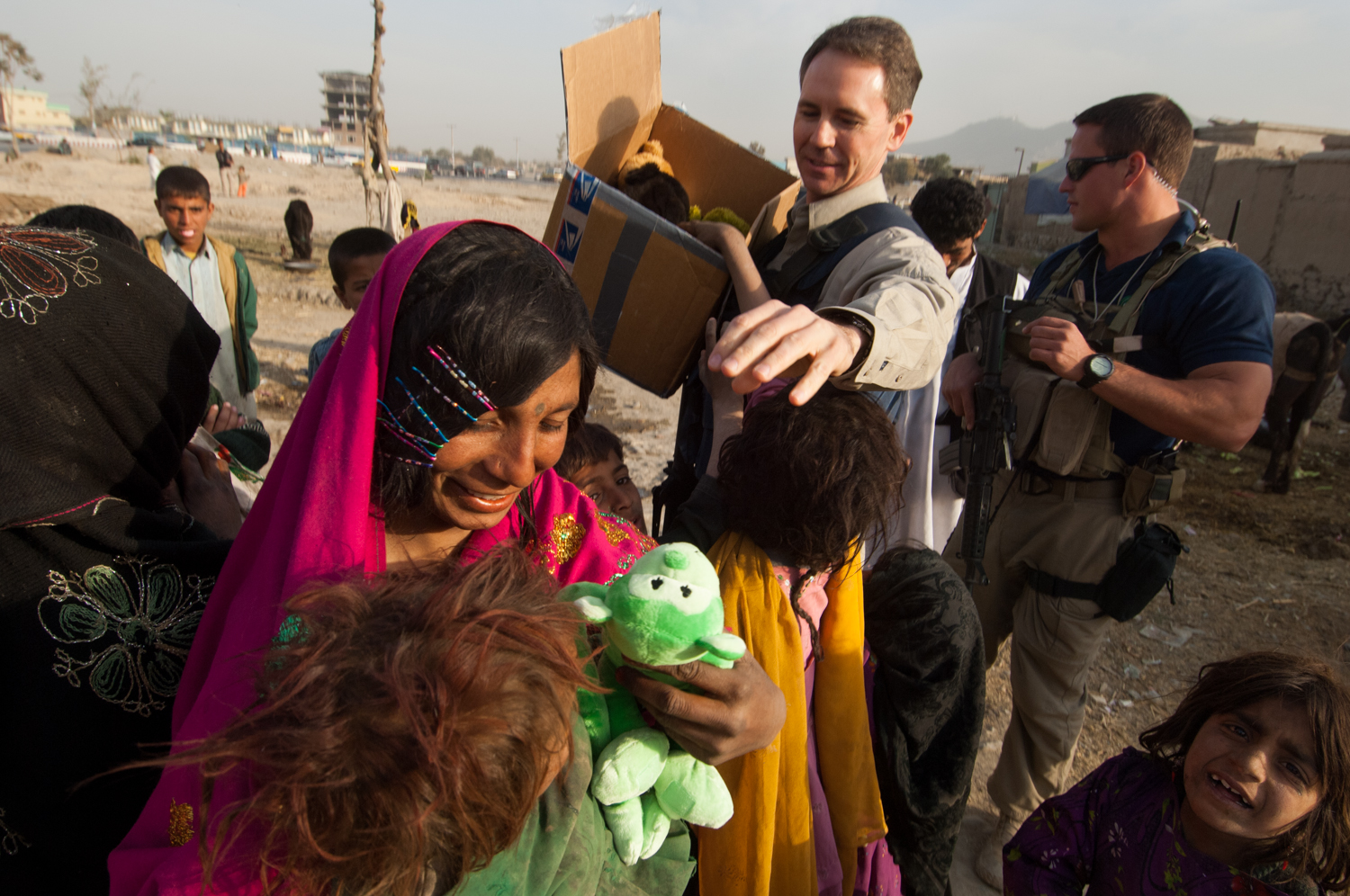  John Ferguson, Country Business Manager for DynCorp International, a publicly traded, multi-million dollar private military company contracted by the US State Department to train the Afghan police force, hands out toys to Afghan children while being