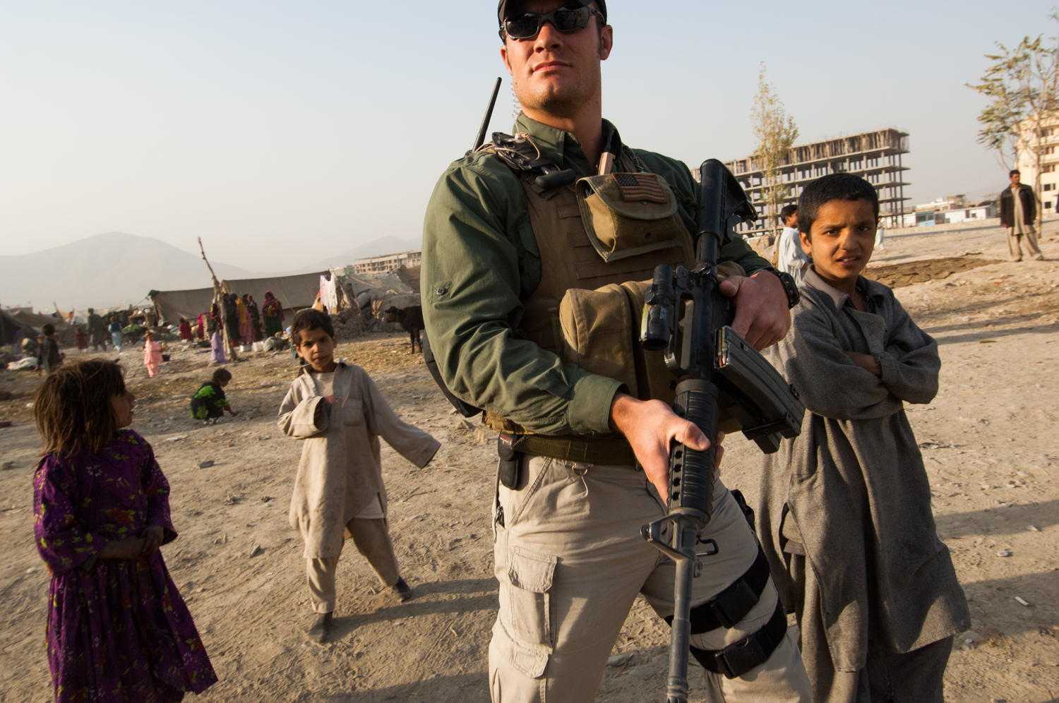  Neil Gary provides security for a DynCorp International official outside a tent camp in Kabul, Afghanistan. 