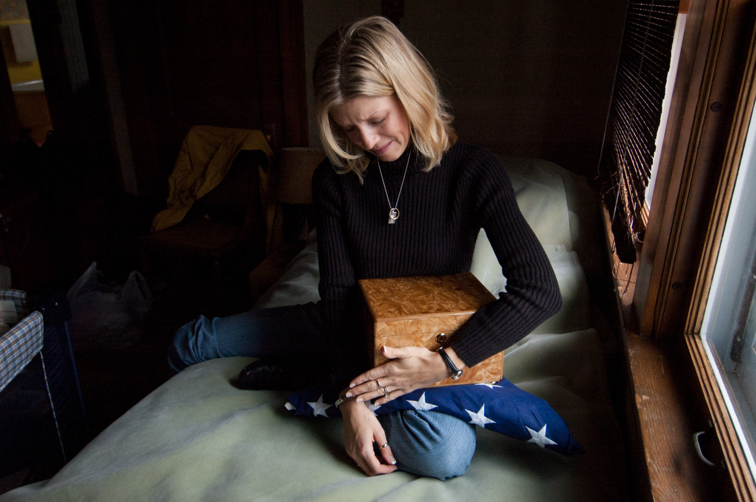  Kristin Kaszynski, wife of security contractor Kyle Kaszynski, sits in her husband's childhood bedroom while holding a box containing his remains in Minneapolis, Minnesota. Mr. Kaszynski was killed December 22, 2005 while working as a contractor for