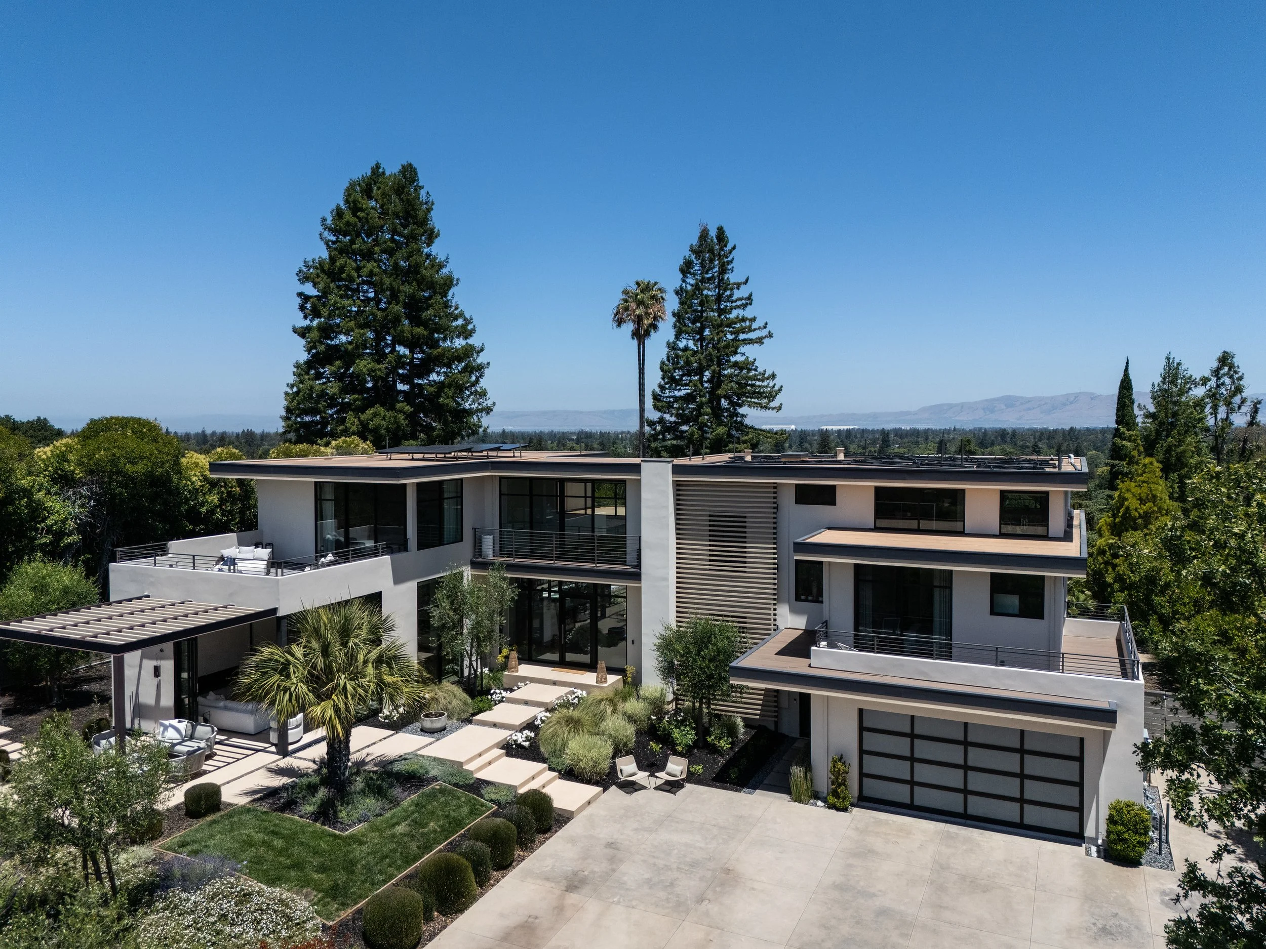 Aerial view of the front of a modern home in Los Altos, CA, with flat roofs, balconies and a wood slat screen