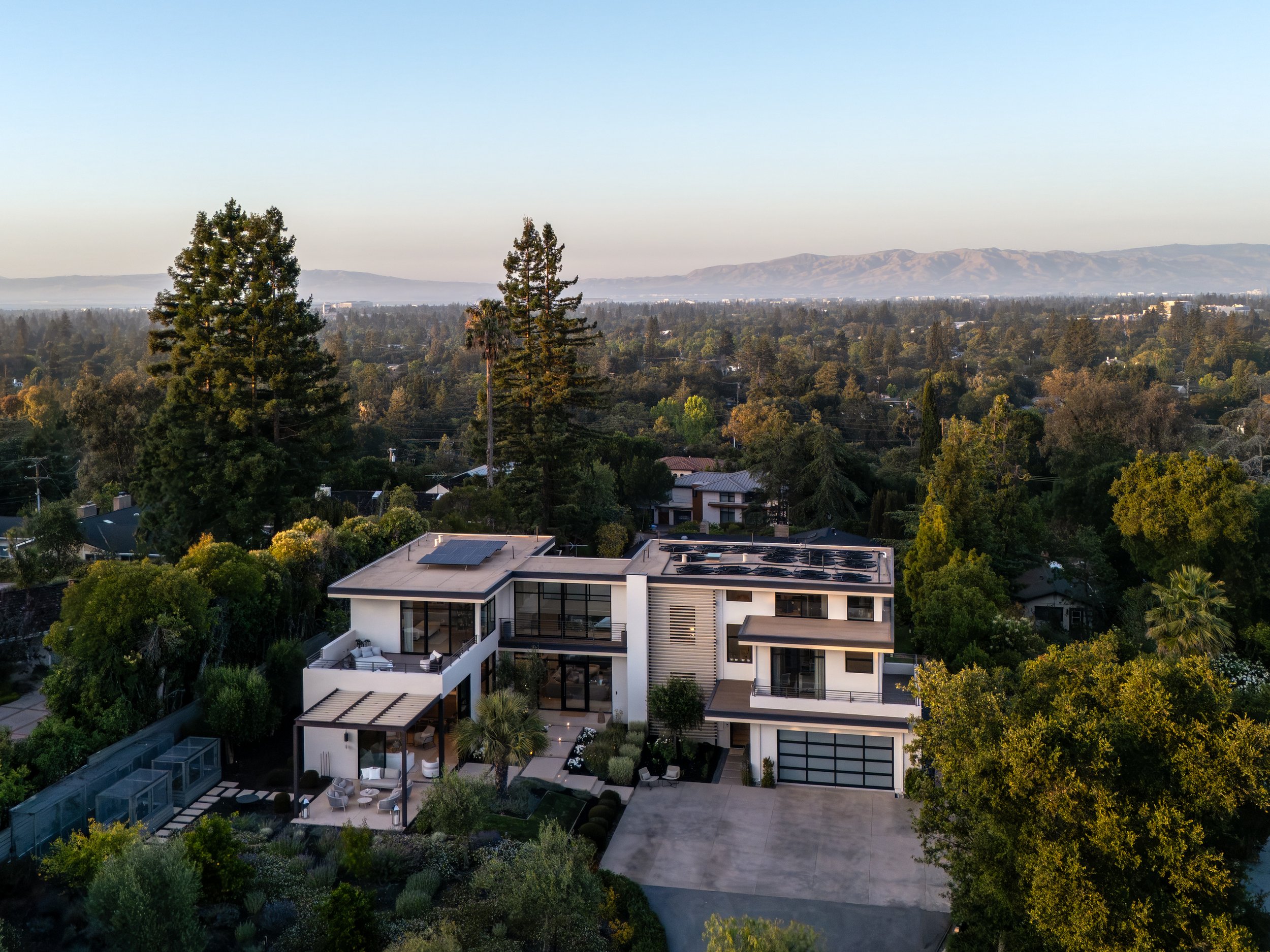 Aerial view at dusk of a modern custom home in Los Altos, CA, with views across Silicon Valley, by Moderna Homes