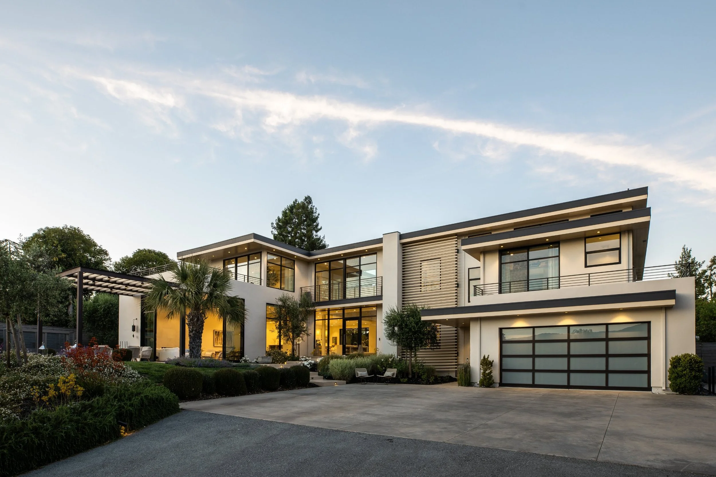 Front exterior of a modern Los Altos, CA home at dusk, with steel-framed windows and a glass garage door
