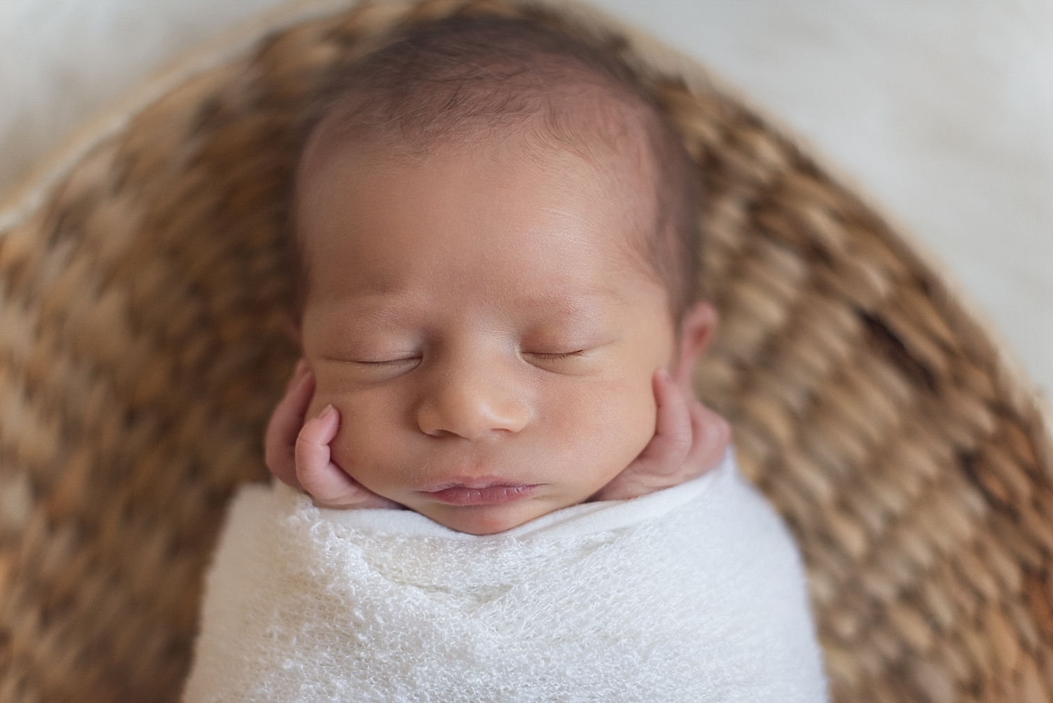  newborn baby wrapped in a swaddle lays in basket 