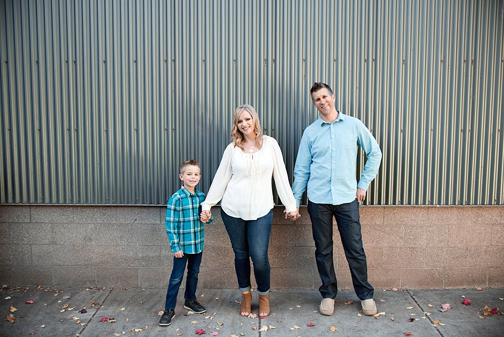  Family poses in front of an urban style building while holind hands in Bend Oregon 