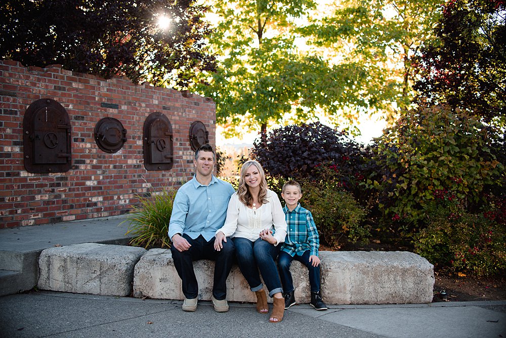  family of three poses by sitting on a brick wall in the Old Mill District in Bend. 