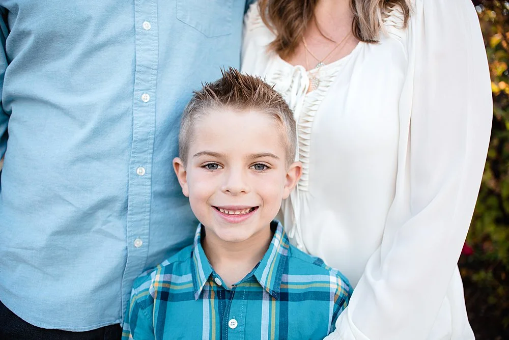 Close up of a boy looking at the camera while his family poses for a photo in the Old Mill District