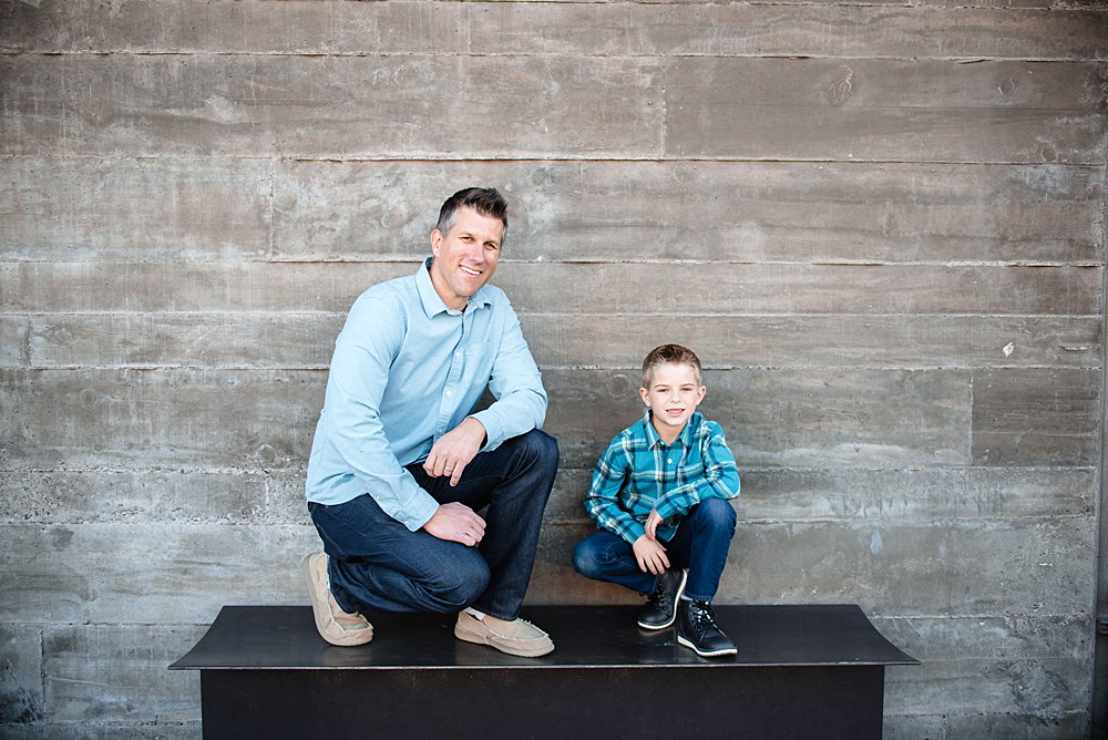  A boy and his dad pose on a bench in front of a stone wall in Bend Oregon 