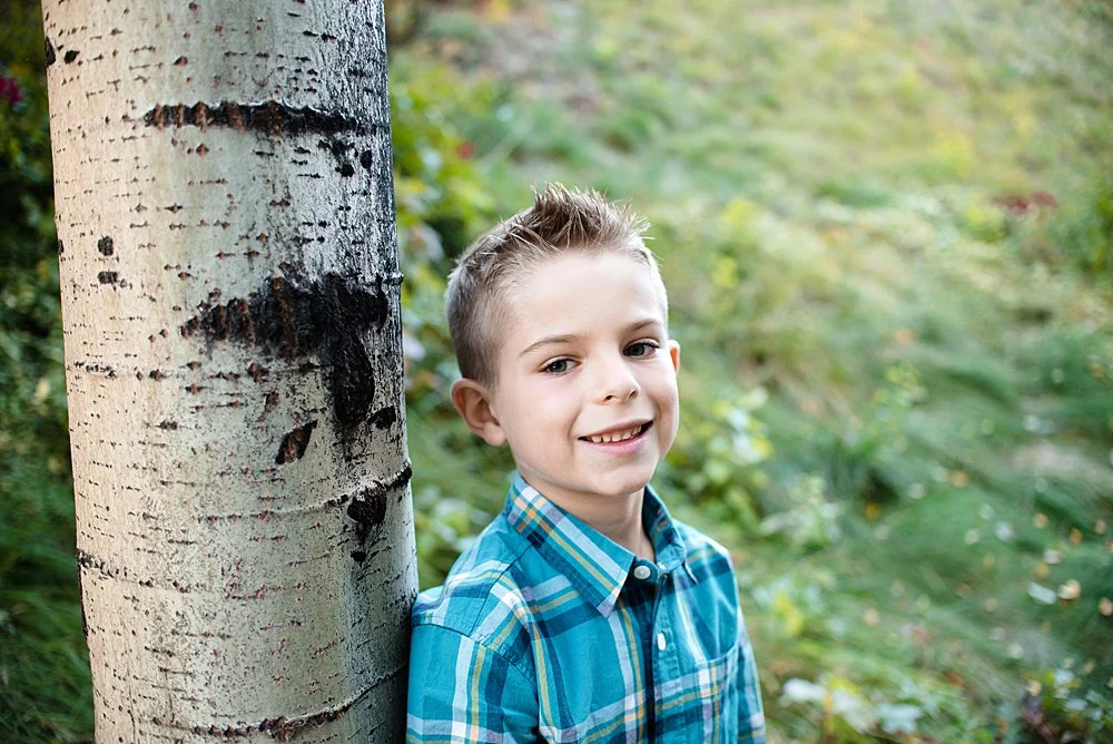 Boy poses next to an aspen tree in the Old Mill District in Bend