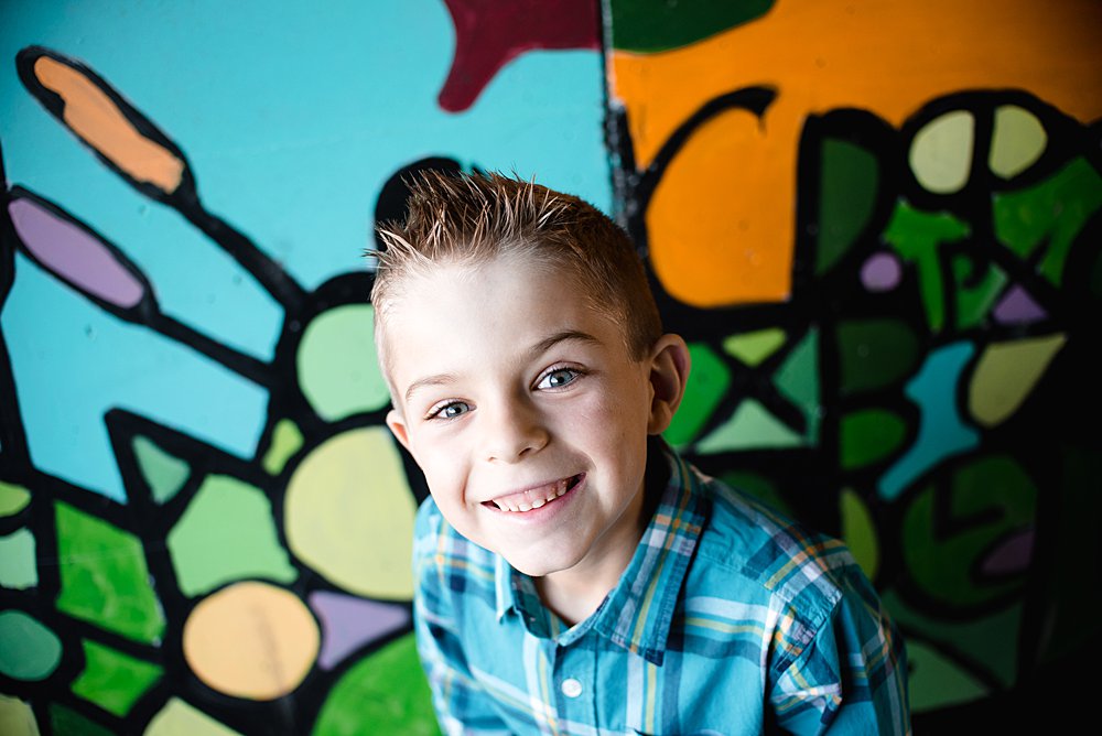  close up of a young boy smiling at the camera in front of a colorful tunnel in the Old Mill District 