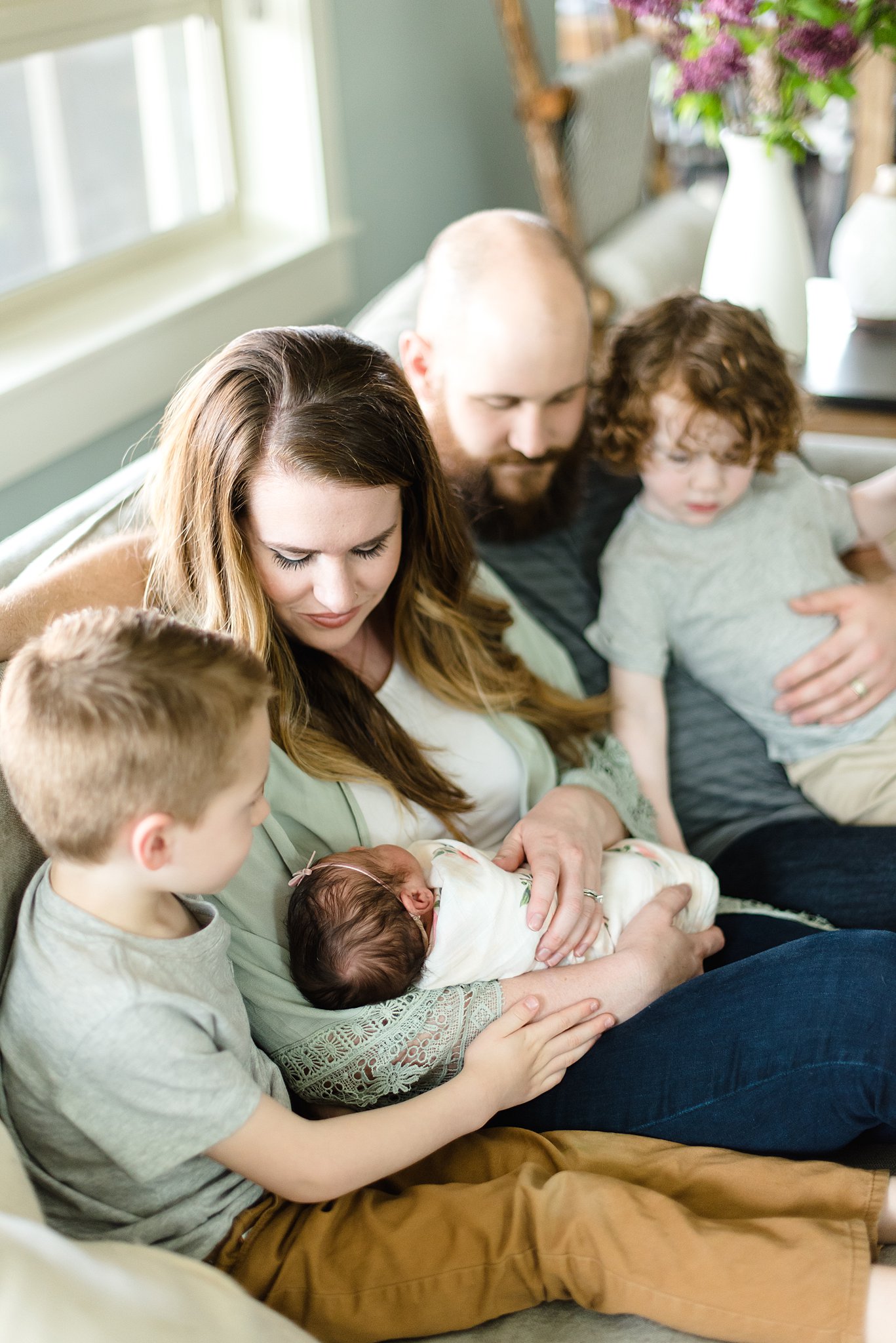  family sits on couch looking at their new baby girl 