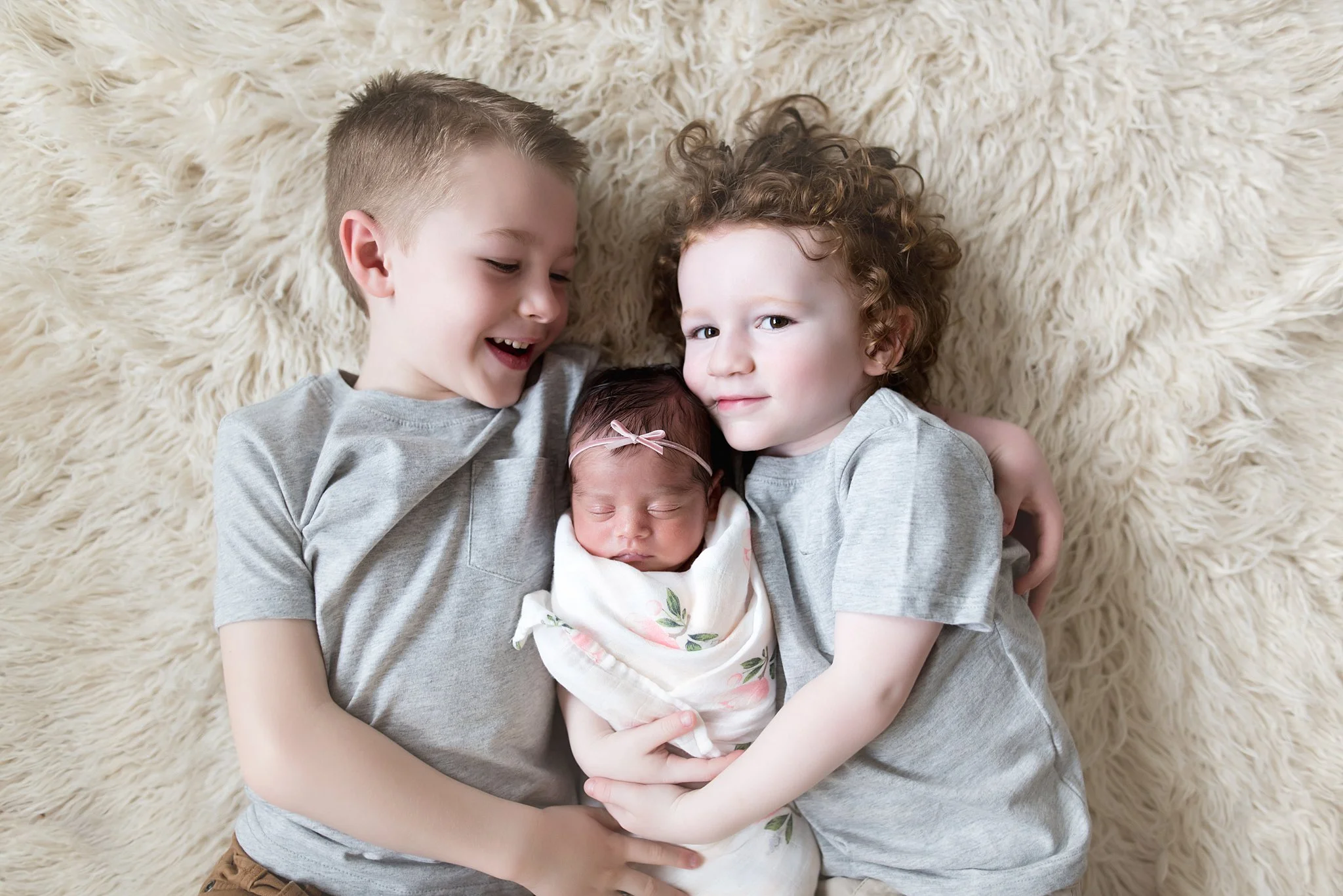 brothers lay together with their new baby sister between them