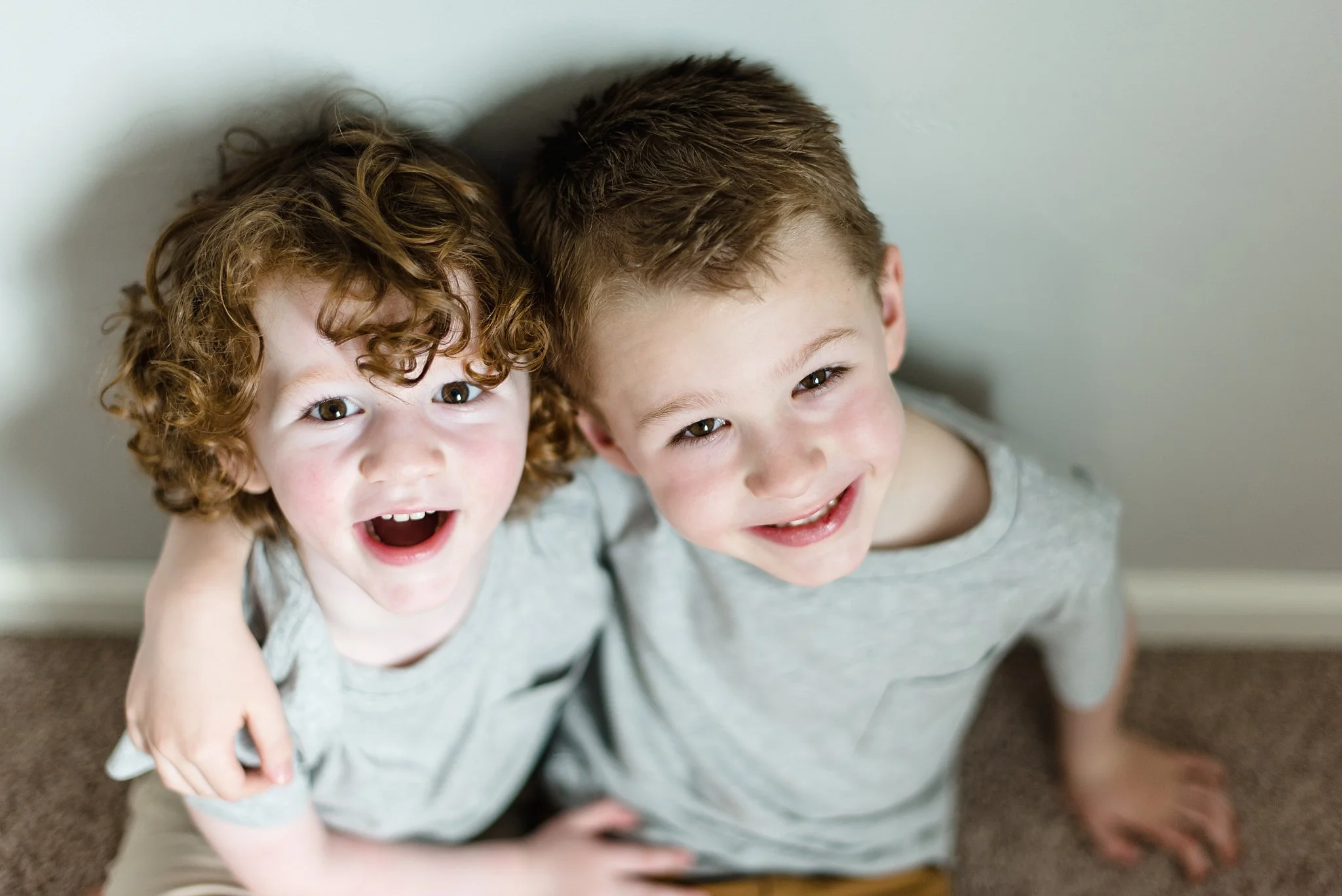 brothers look up at the camera smiling and hugging each other