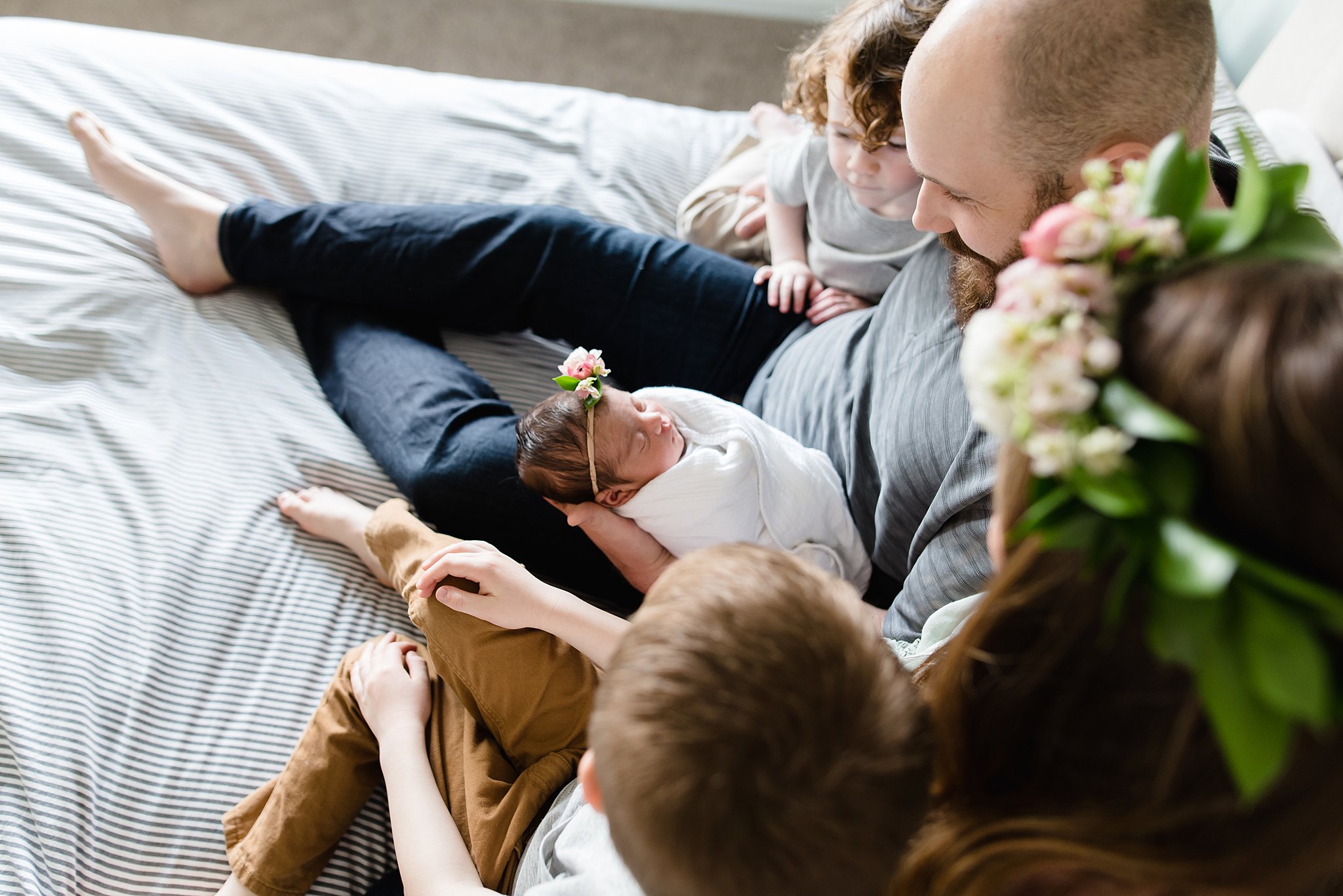  family snuggles on a bed with their three children 