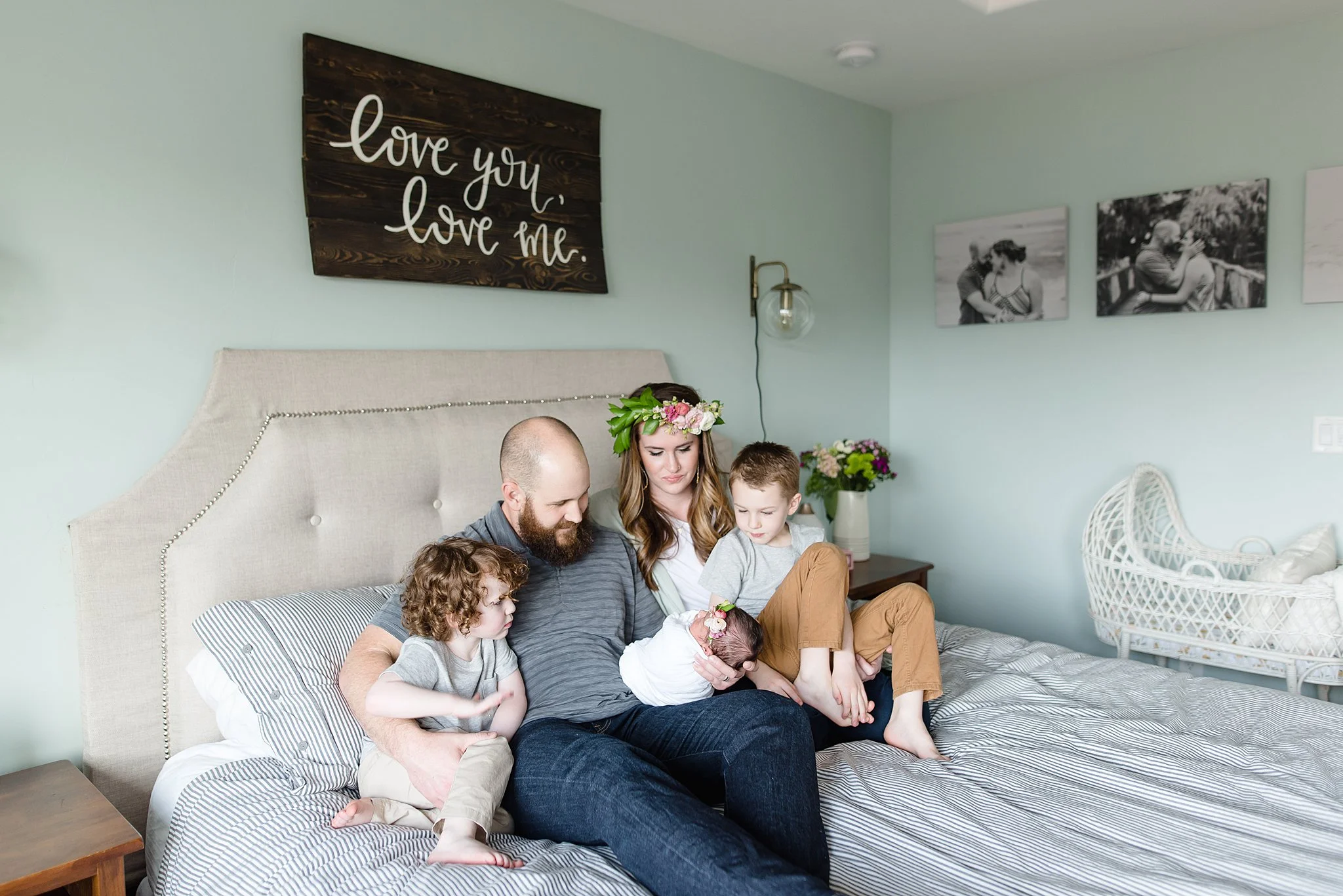 family lays on bed gazing at their new baby girl