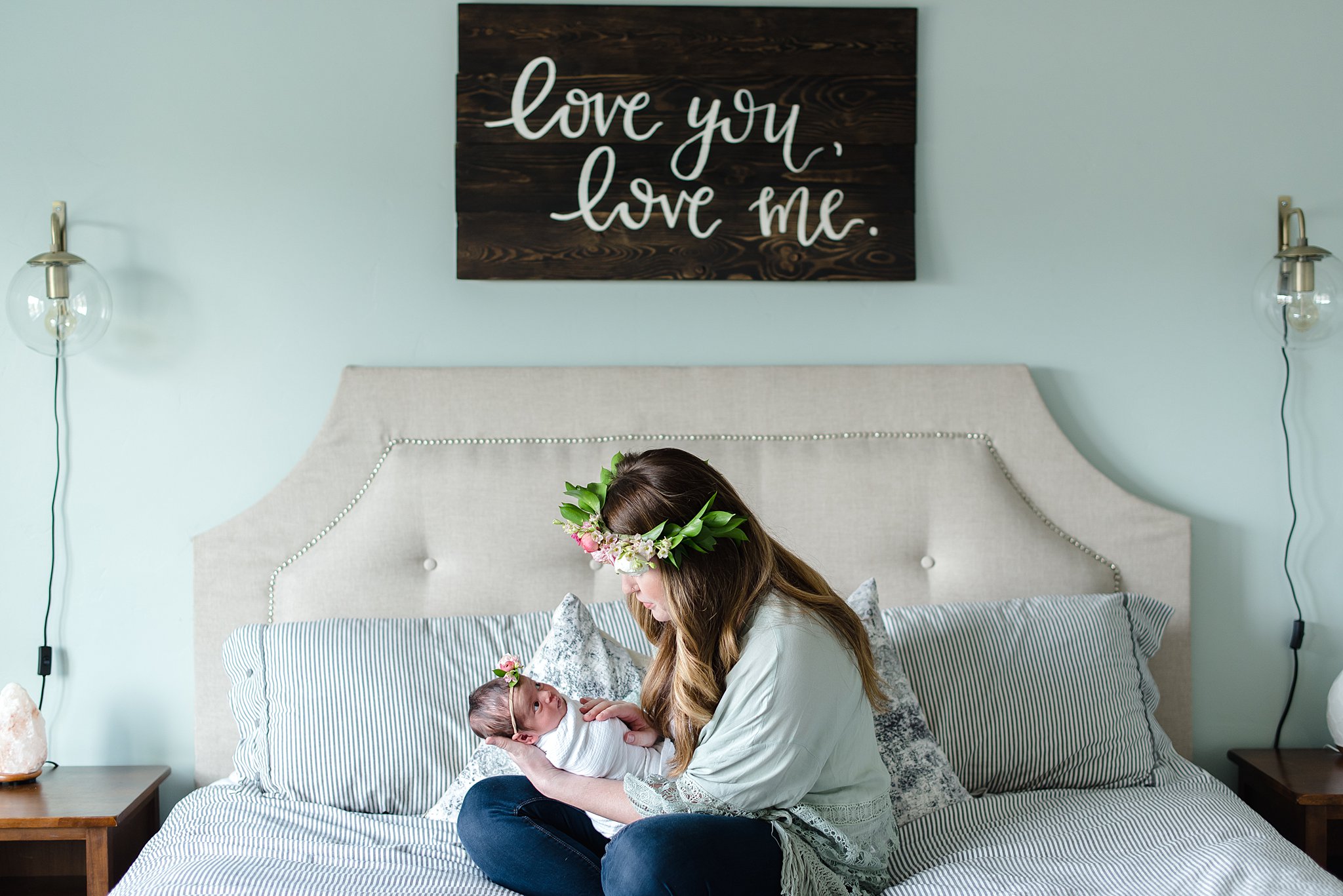  mom holds her baby girl on the bed 