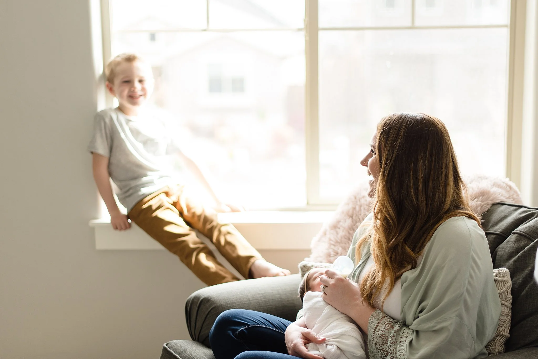 mom laughs with her son while holding her baby girl