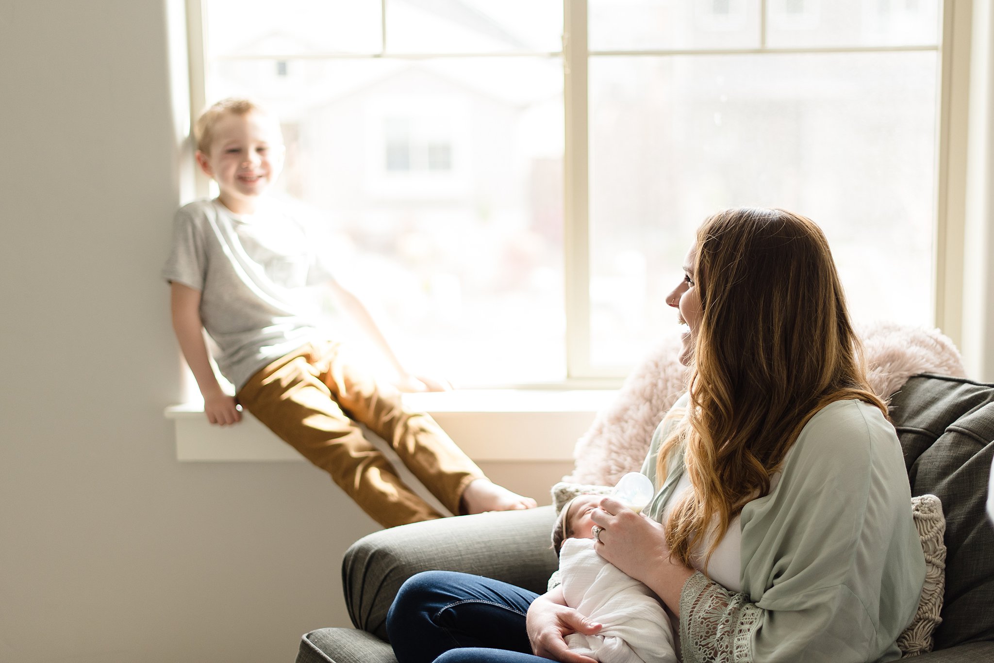  mom laughs with her son while holding her baby girl 