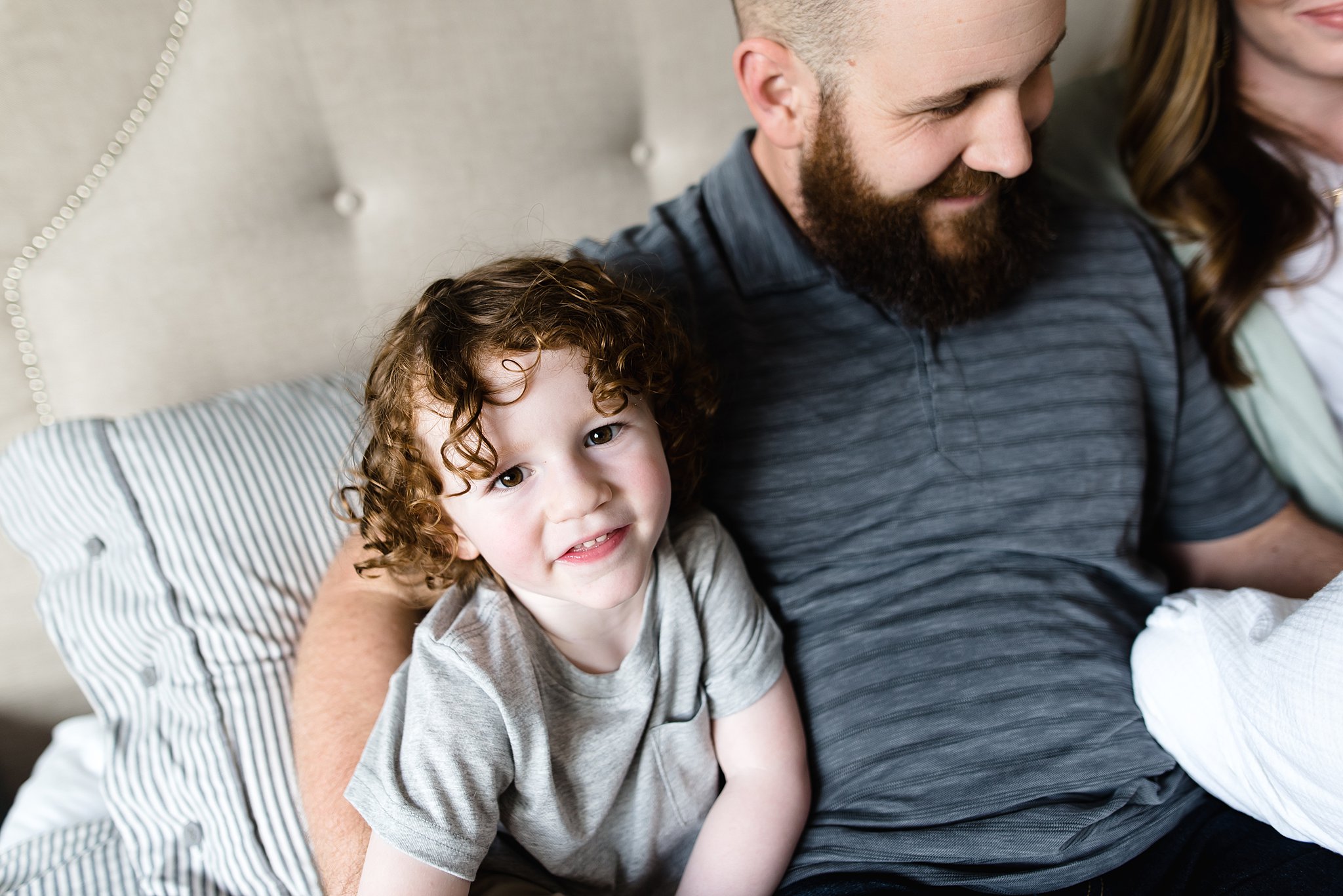  a boy looks up at the camera snuggled next to his dad 