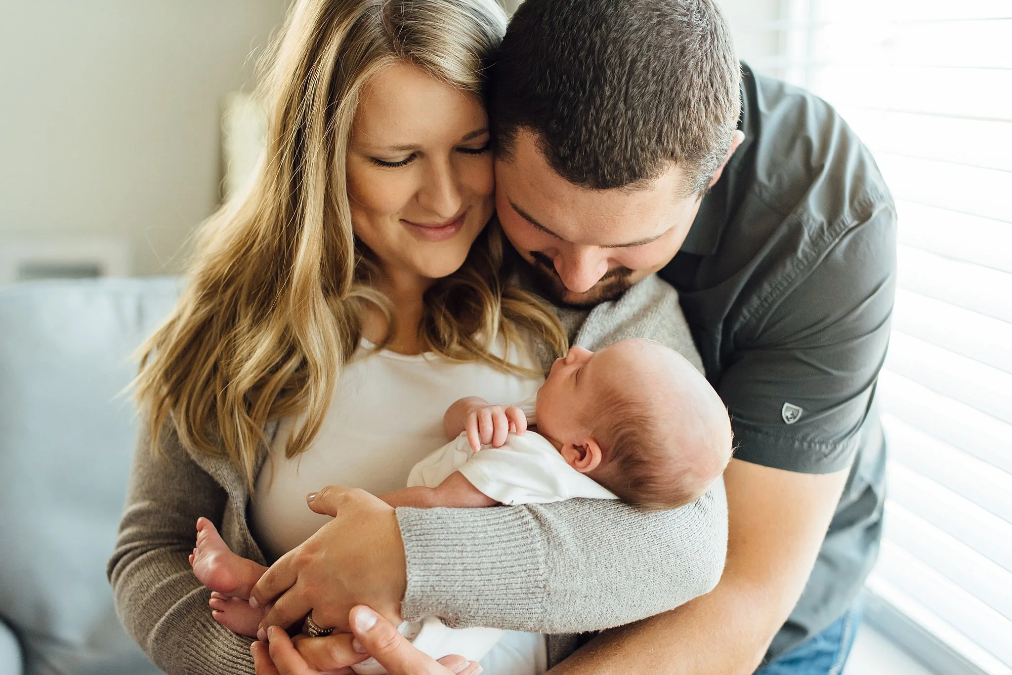 A new mother and father gaze and snuggle their newborn baby boy.