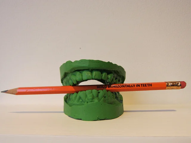 “Green Teeth” by Alix Lambert (MFA AP Faculty) is included in the SPRING/BREAK room curated by Angela Conant.
“Entering the room curated by Angela Conant the theme of pencils immediately jumps out, but how exactly they work into all the art isn’t evident until you read further and find that Conant is playing off a 1998 experiment that asked subjects to keep pencils between their teeth while reading funny statements, discovering that they found them more funny with the pencils than without (the pencils triggering smiling muscles).”
Hyperallergic reviews SPRING/BREAK , including a room curated by Art Practice Participant Angela Conant (MFA AP13).
