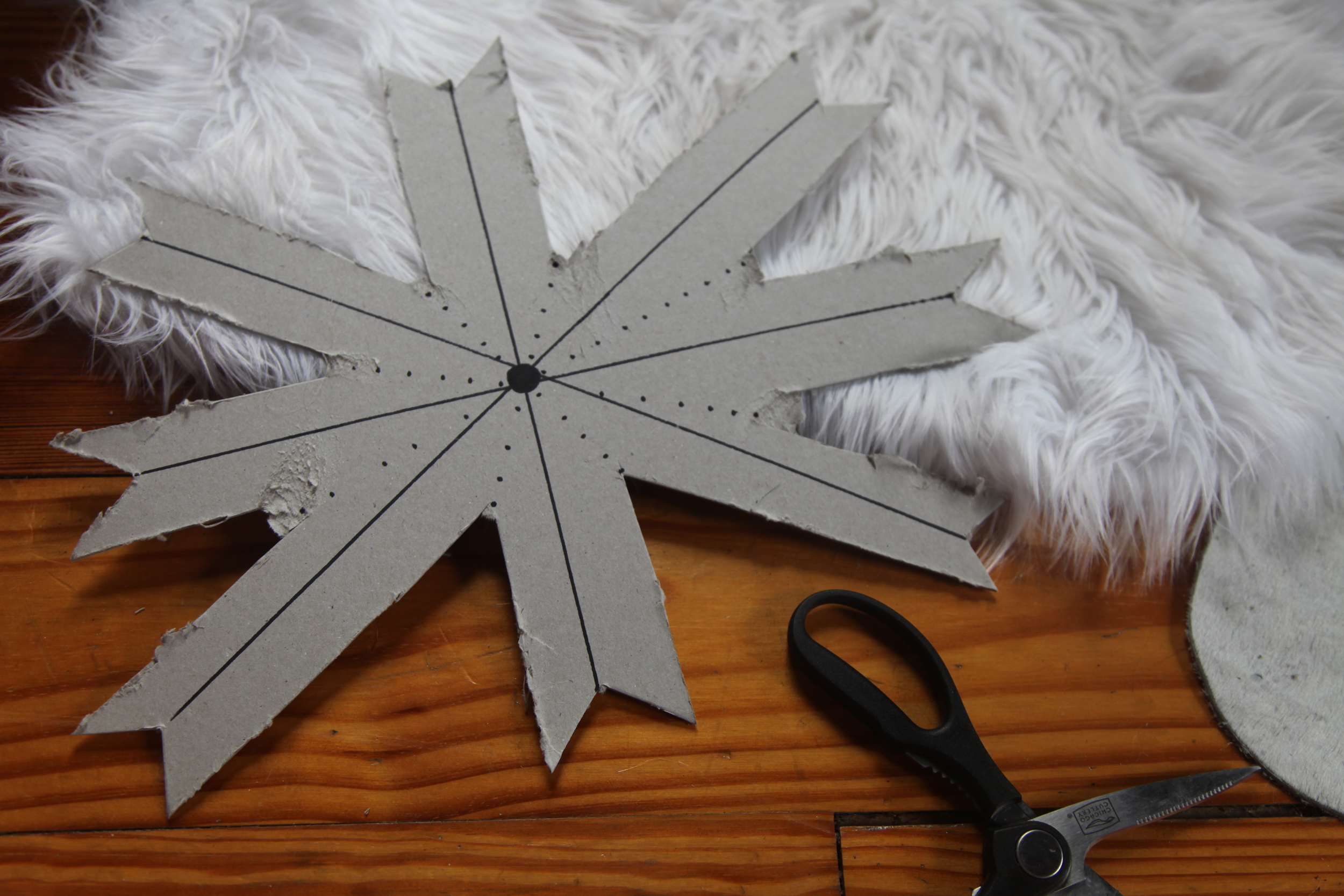 Step Two: Create an Outline Your cardboard cutout lines should resemble that of a compass. Start by drawing a cross with lines going North, South, East, and West then Northeast, Northwest, Southeast, and Southwest. These lines will be your center points on your 8 arrows. Draw dotted lines between each arrow, these will be your valley points and will help with cutting. Don't stress if your lines or cuts don't end up perfect, the matchsticks will hide all of it. It is really just a guideline and extra support that makes the creating process a little bit easier. I made each arrow around 2" thick and 7" long, some will be longer and some shorter so I kept the extra length just to be safe.