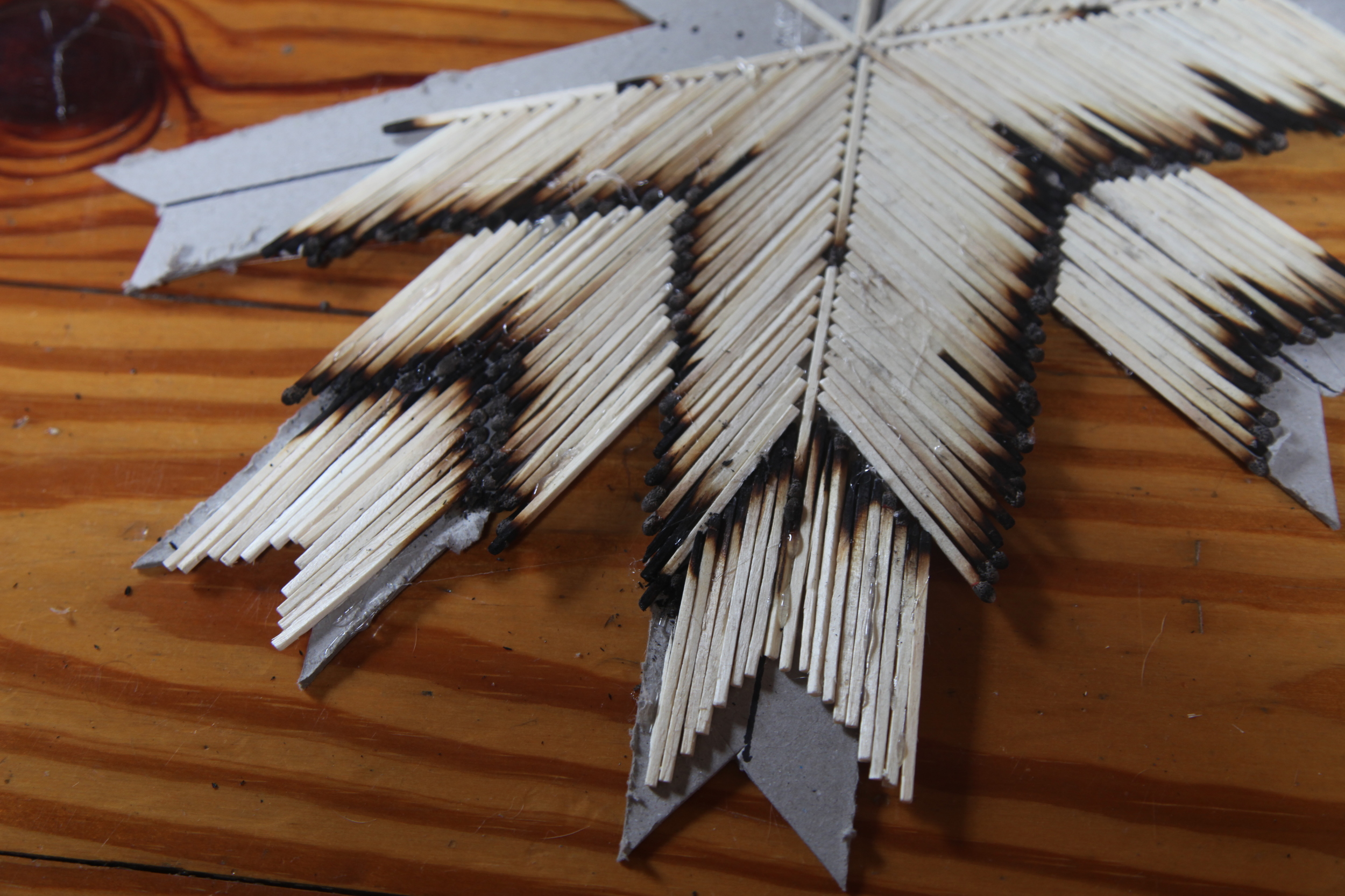 East & West arrows have three tiers to give extra dimension to the overall piece. The arrow is created the same way except the burnt edges are now facing inward and connecting with the burnt edge of the second tier. It also shouldn't be as wide. I shortened my third tier by four matches and then cut off the excess cardboard.