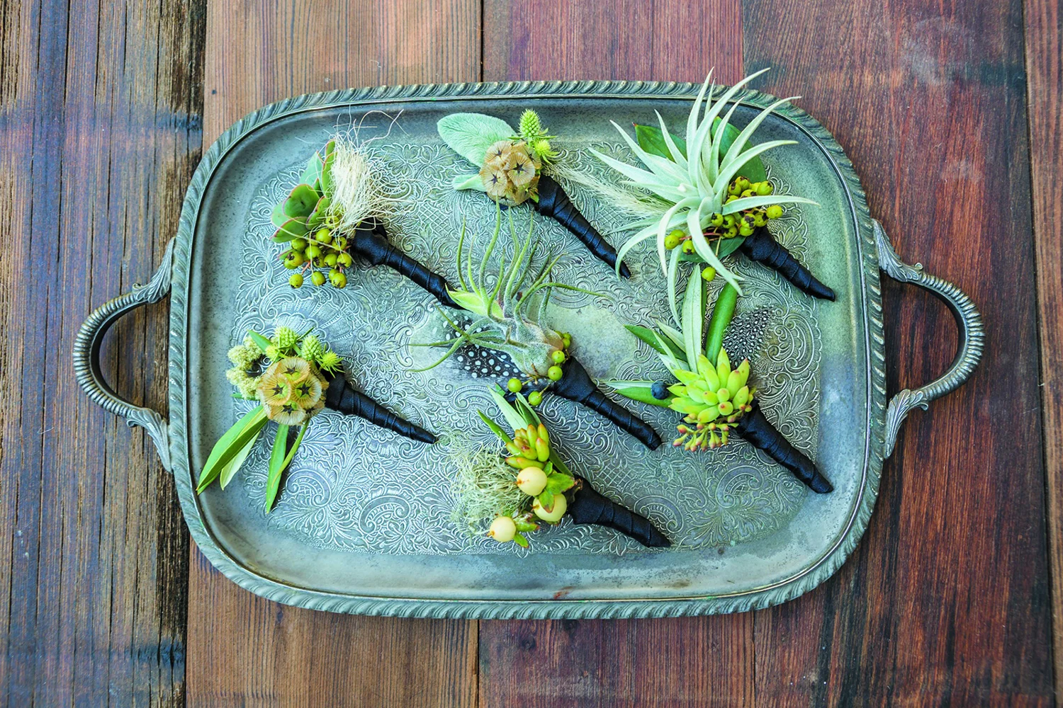 Drought Tolerant Boutonnieres using succulents, tillandsias, spanish moss, sage, nandina berry, scabiosa pod, feathers, and cornsilk.