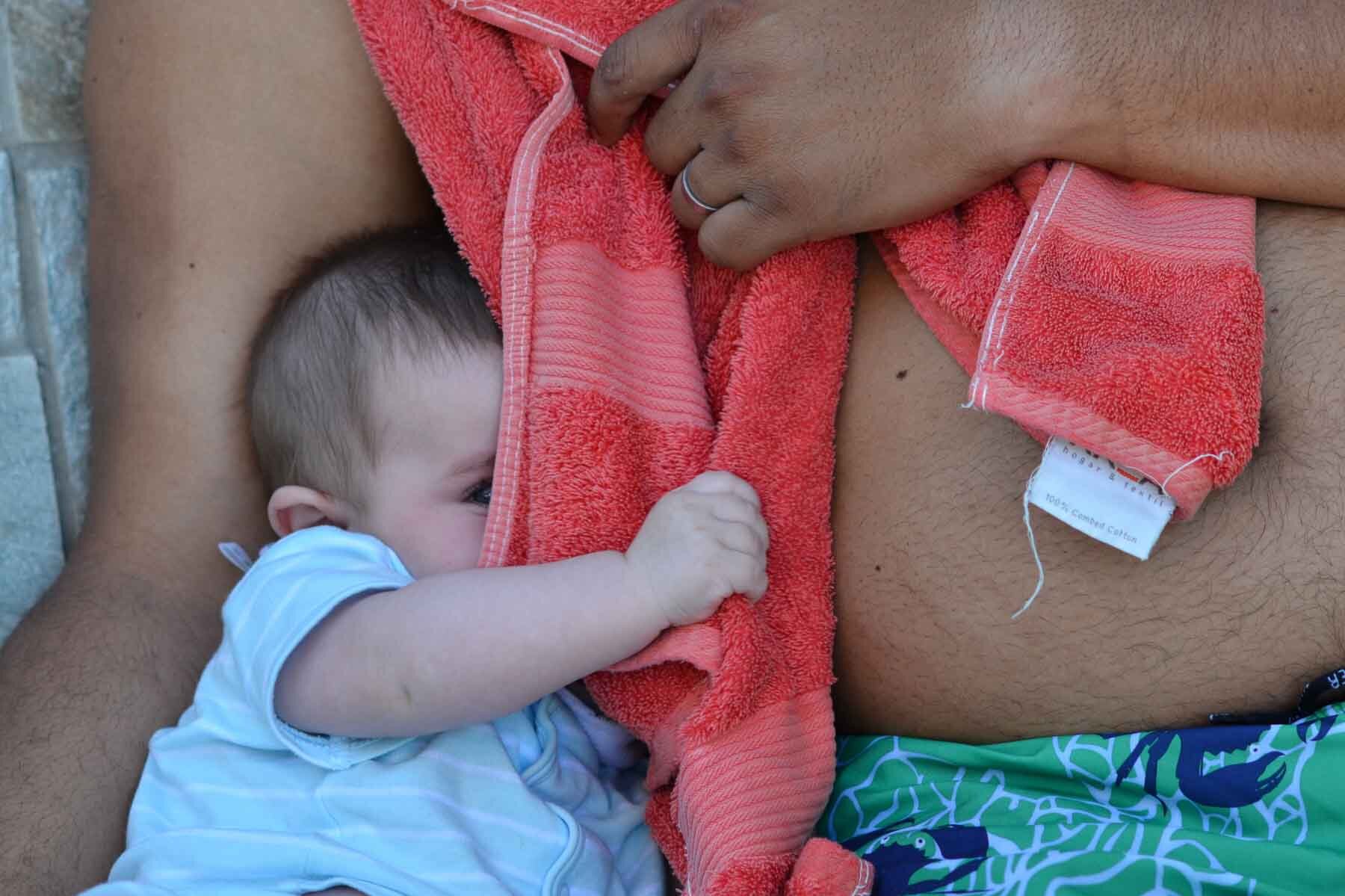  A young baby with her father beside the swimming pool on a hot summer afternoon. Peep-bo! 